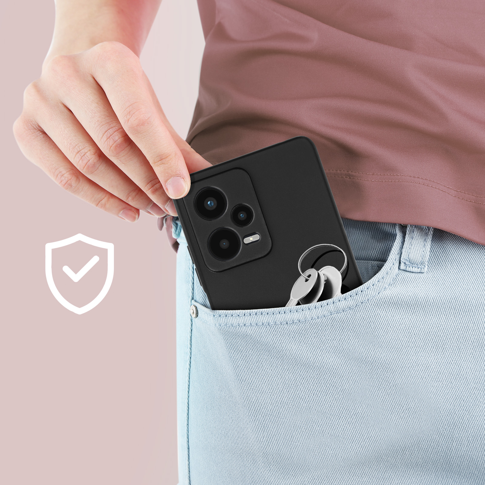 Hand steckt ein schwarzes Telefon mit Schlüsseln in eine Tasche. Jeans-Tasche und ein rosa Hemd im Hintergrund.