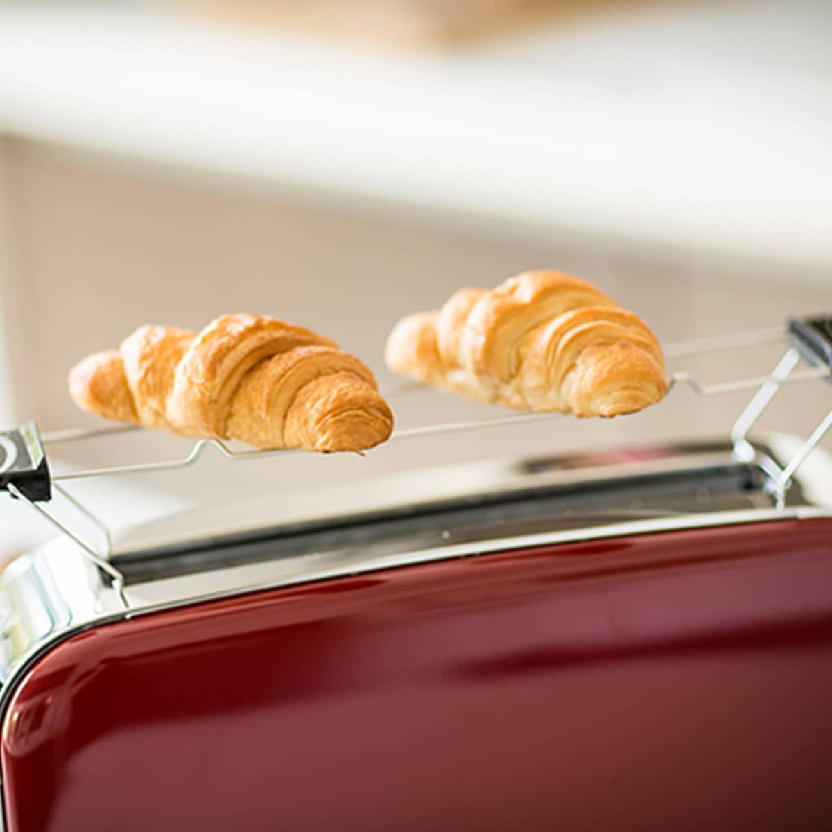 Roter Toaster mit zwei goldenen Croissants, die oben aufliegen.