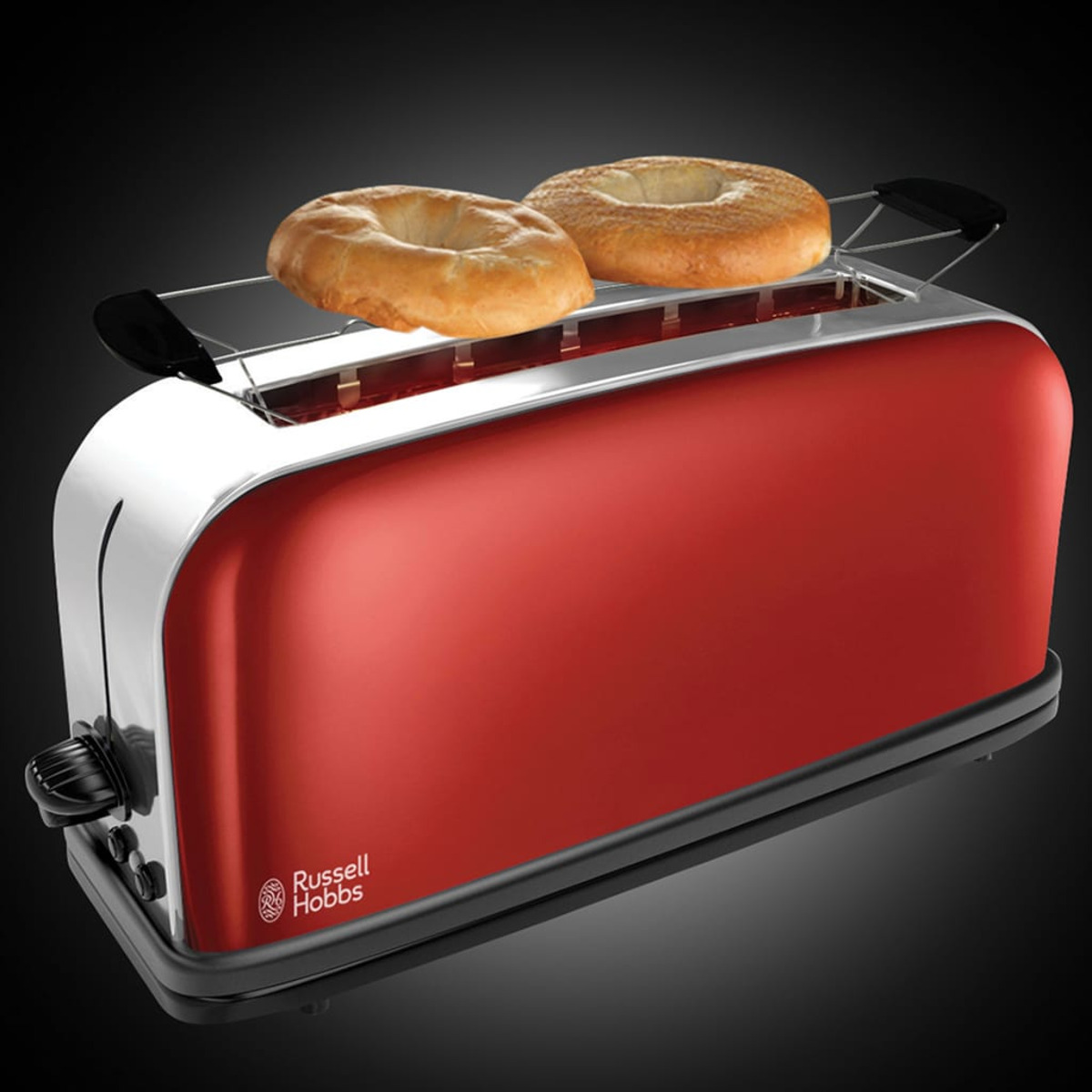 Roter Toaster mit zwei Bagels, auf schwarzem Untergrund, dunkler Hintergrund.