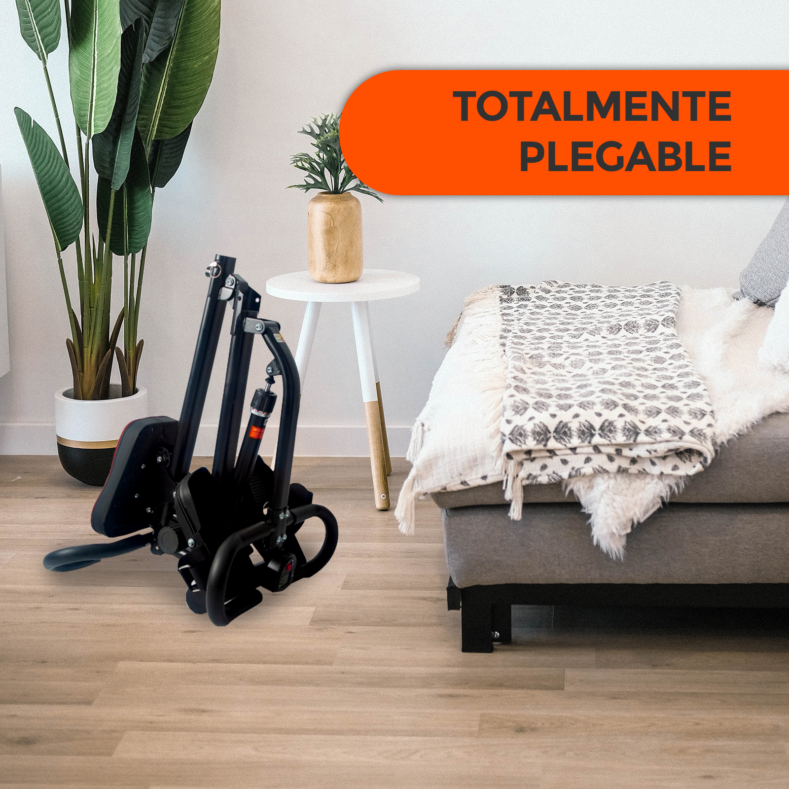 Máquina de remo plegable en suelo de madera. Fondo: sofá, planta, mesa con jarrón.