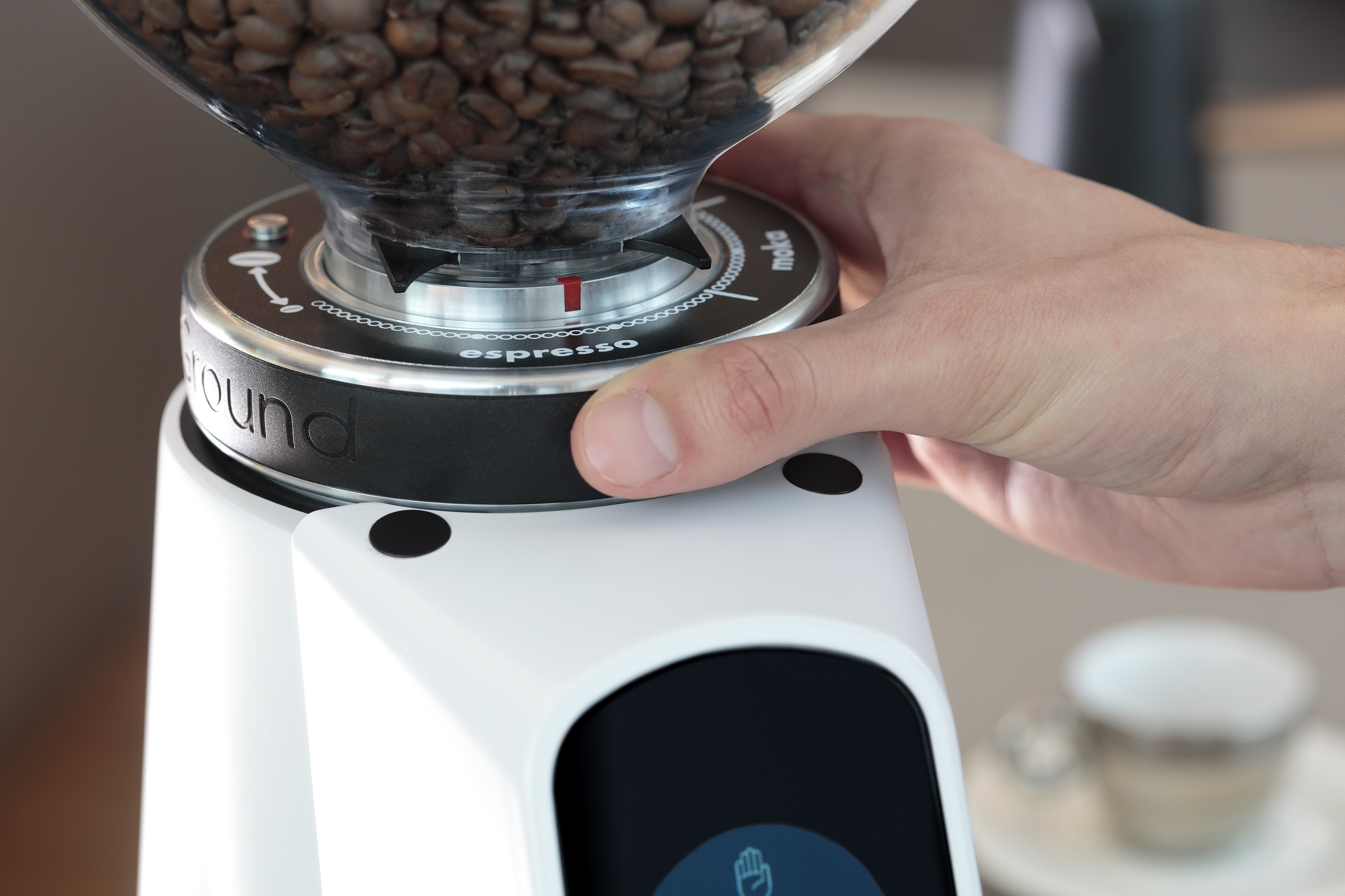 Hand verstellt Kaffeemühle, Bohnen im Trichter. Espresso-Einstellung angegeben.