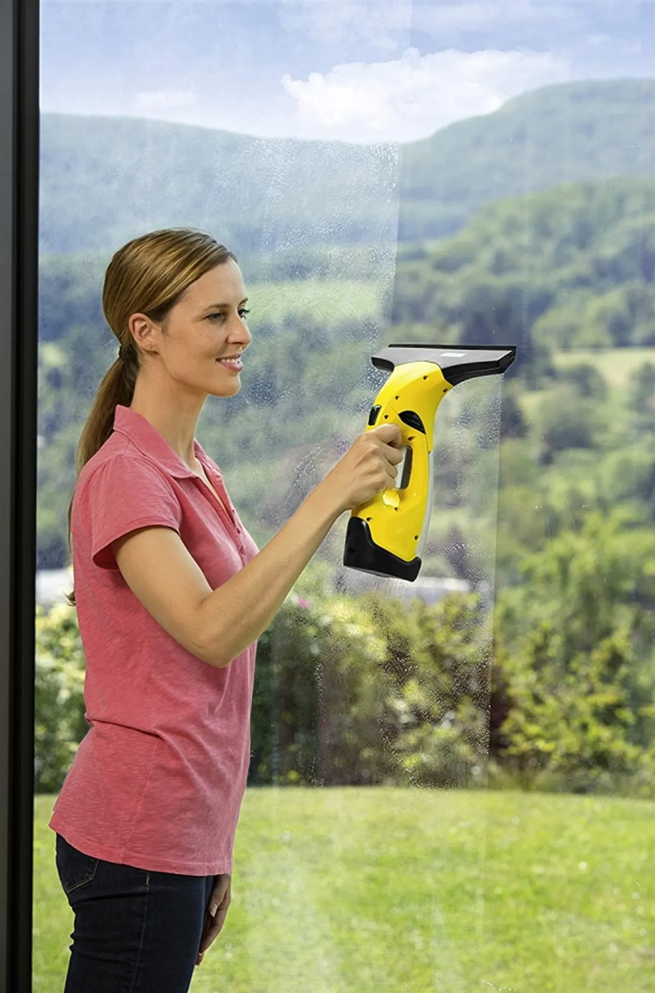 Donna che pulisce una finestra con un pulitore per vetri giallo e nero.