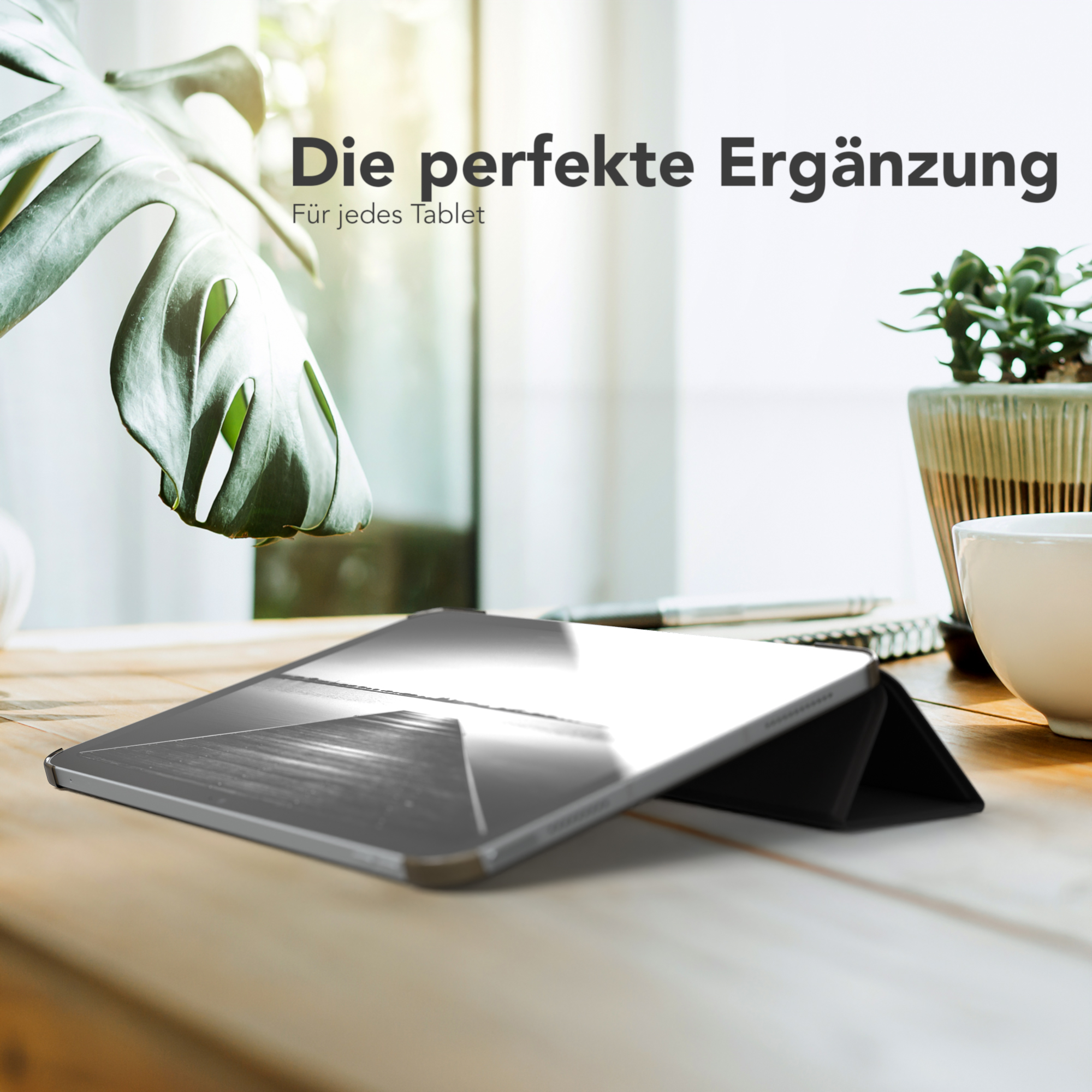 Ein Tablet in einer schwarzen Hülle auf einem Holztisch mit dem Text „Die perfekte Ergänzung“.