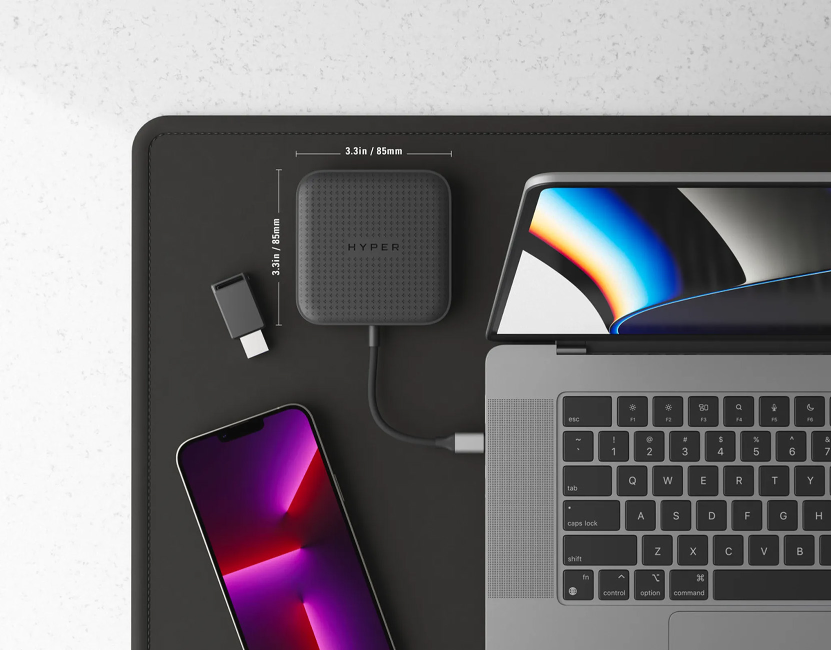 Opstelling met een laptop, telefoon en hub. Alle items liggen op een zwarte bureaumat.