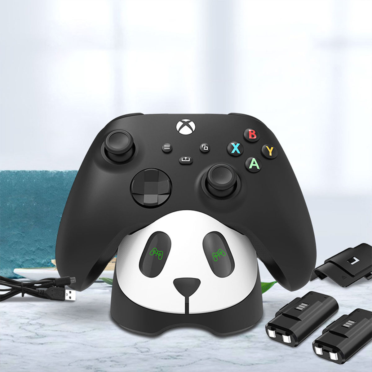 Schwarzer Gamecontroller-Ständer im Panda-Design, der einen schwarzen Controller hält. Drei zusätzliche schwarze Zubehörteile.