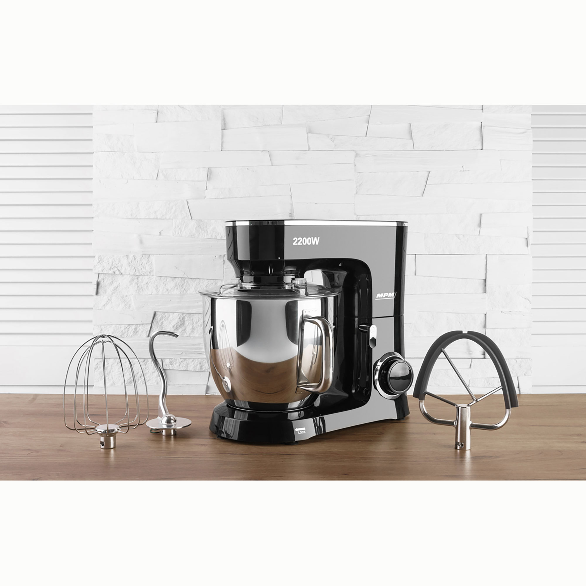 Ein schwarzer Küchenmixer mit Aufsätzen aus Edelstahl auf einer Holzoberfläche.