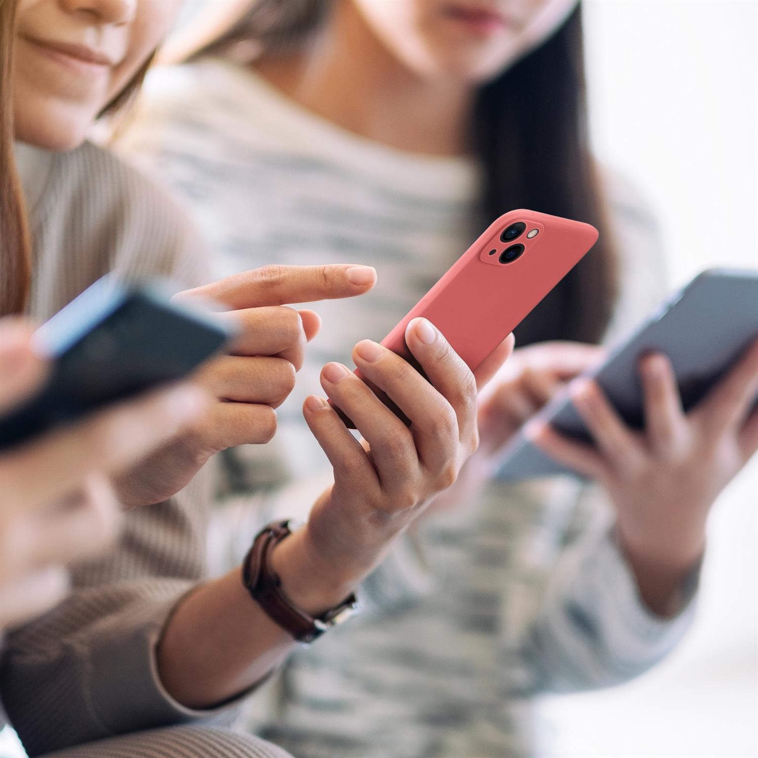 Drei Personen halten Smartphones, zwei halten rosa und graue Telefone.