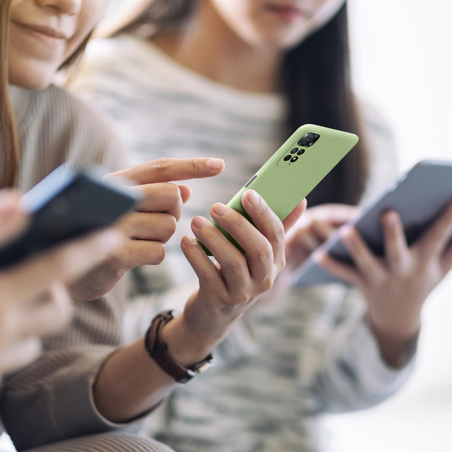 Drei Personen halten Telefone. Ein Telefon in einer grünen Hülle. Fokus auf Telefone und Hände.