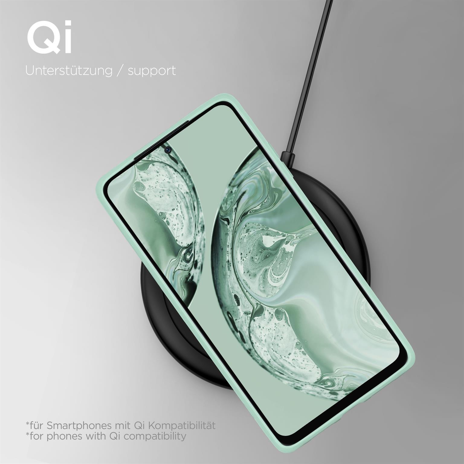 Ein Smartphone auf einer kabellosen Ladestation, in einer mintfarbenen Handyhülle.