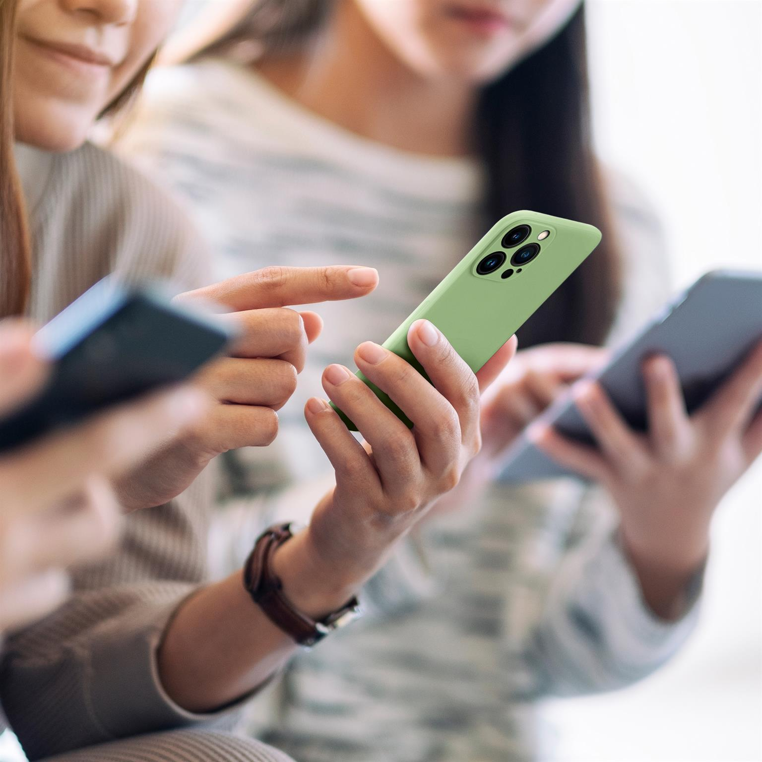 Zwei Frauen halten Telefone. Eines ist grün, das andere schwarz. Sie schauen auf die Bildschirme.