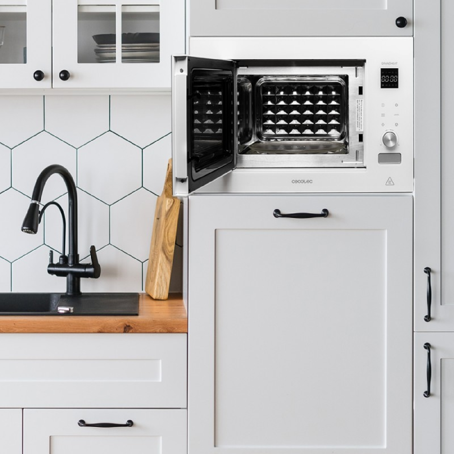 Mikrofalówka w białej szafce kuchennej, otwarte drzwi, z deską do krojenia.