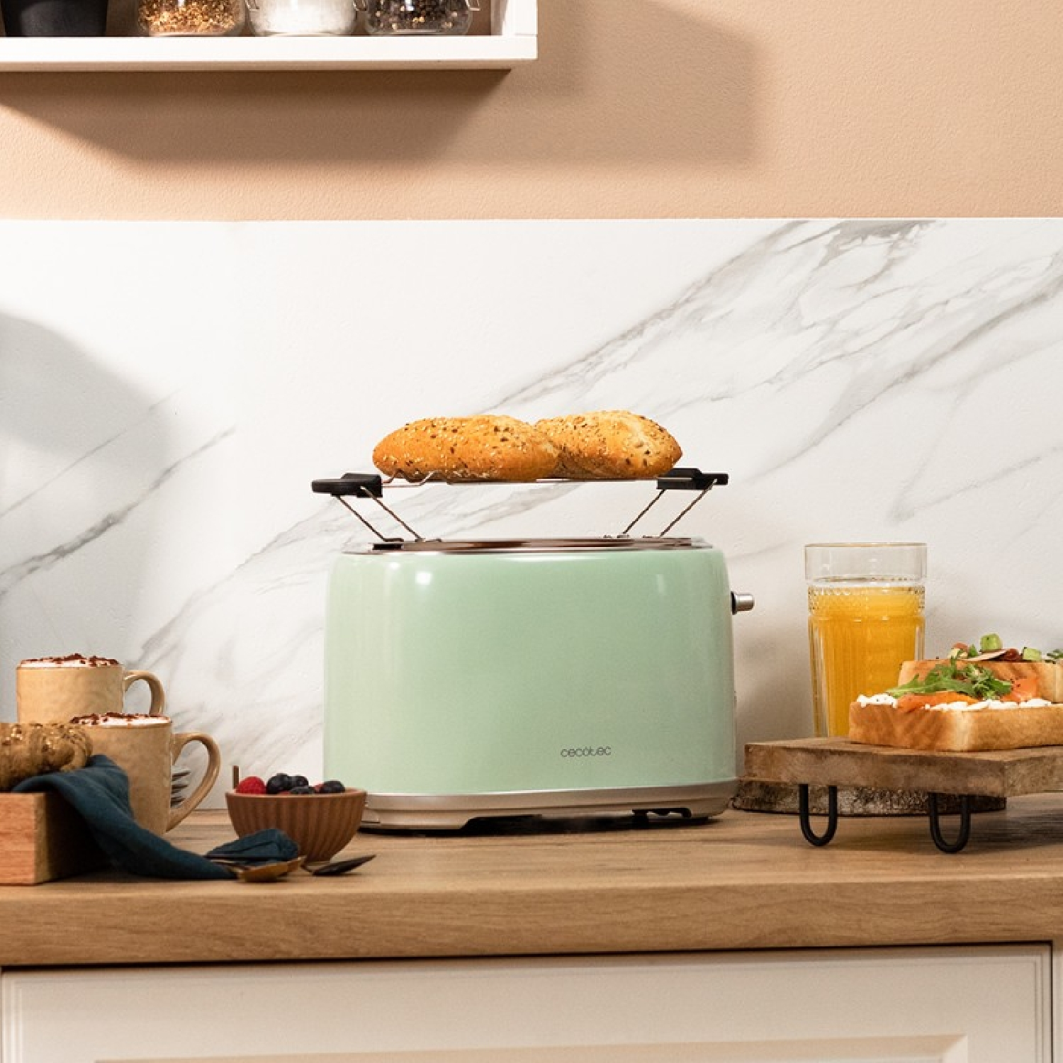 Tostapane verde con pane. Accanto, un bicchiere di succo e toast su un vassoio di legno. Ci sono anche tazze e bacche.