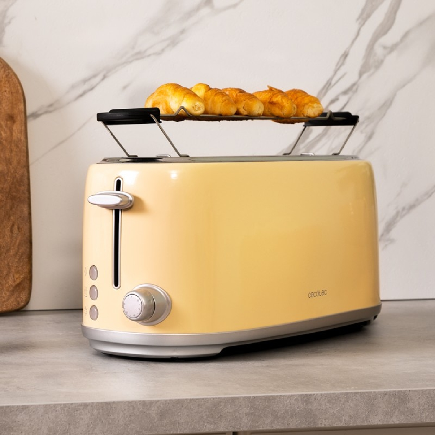 Gelber Retro-Toaster mit Croissants auf einem Rost. Auf einer grauen Arbeitsplatte.