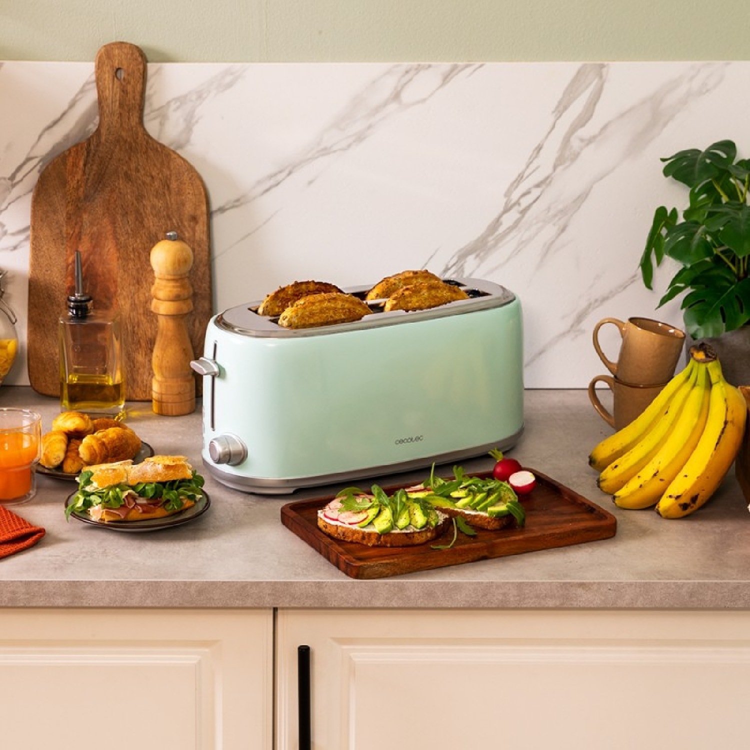 Ein mintgrüner Toaster mit Toast, Sandwiches und Obst auf einer Küchenarbeitsplatte.