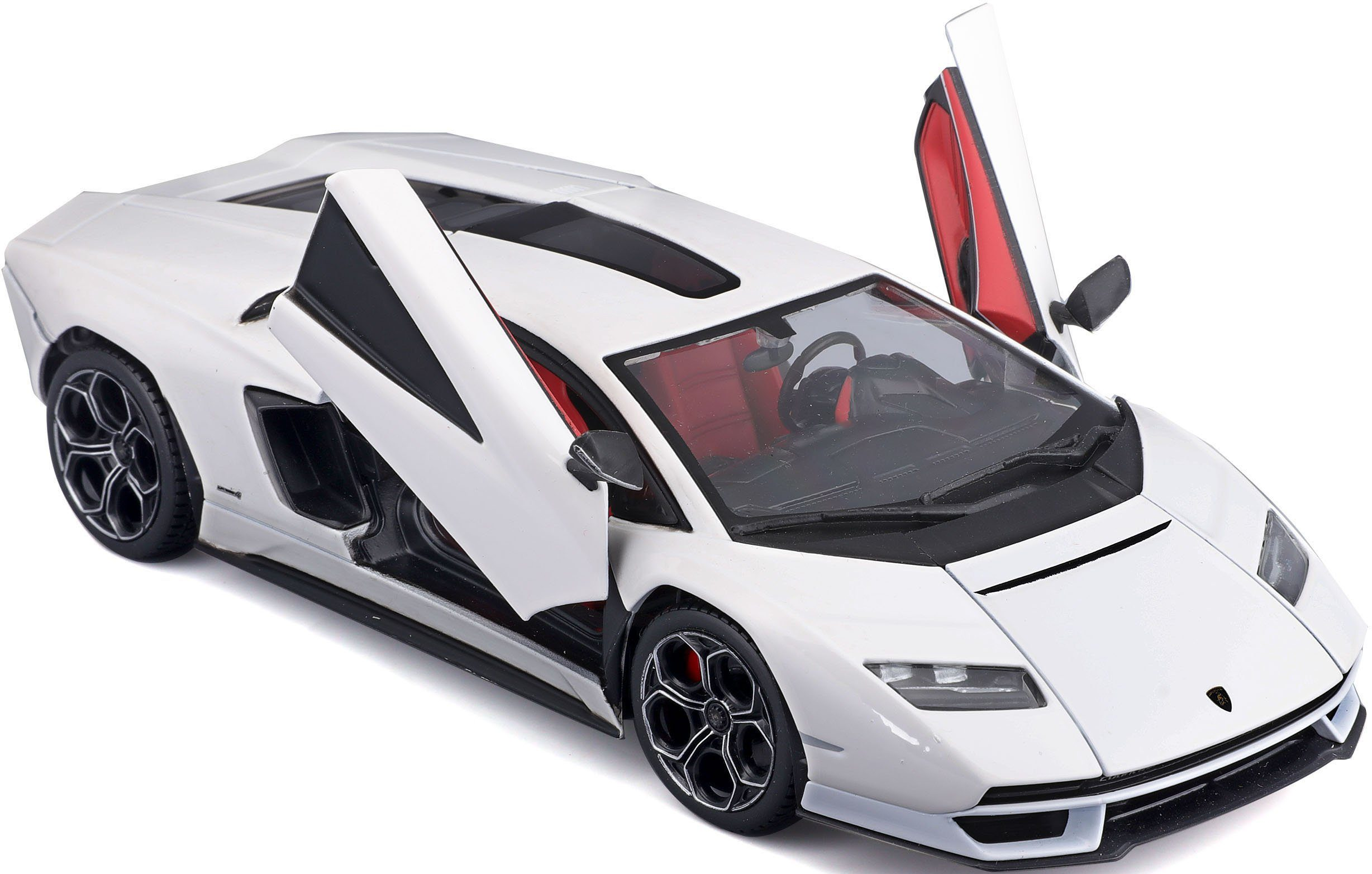 Biały samochód Lamborghini, otwarte drzwi, na białym tle. Widoczne czerwone wnętrze.