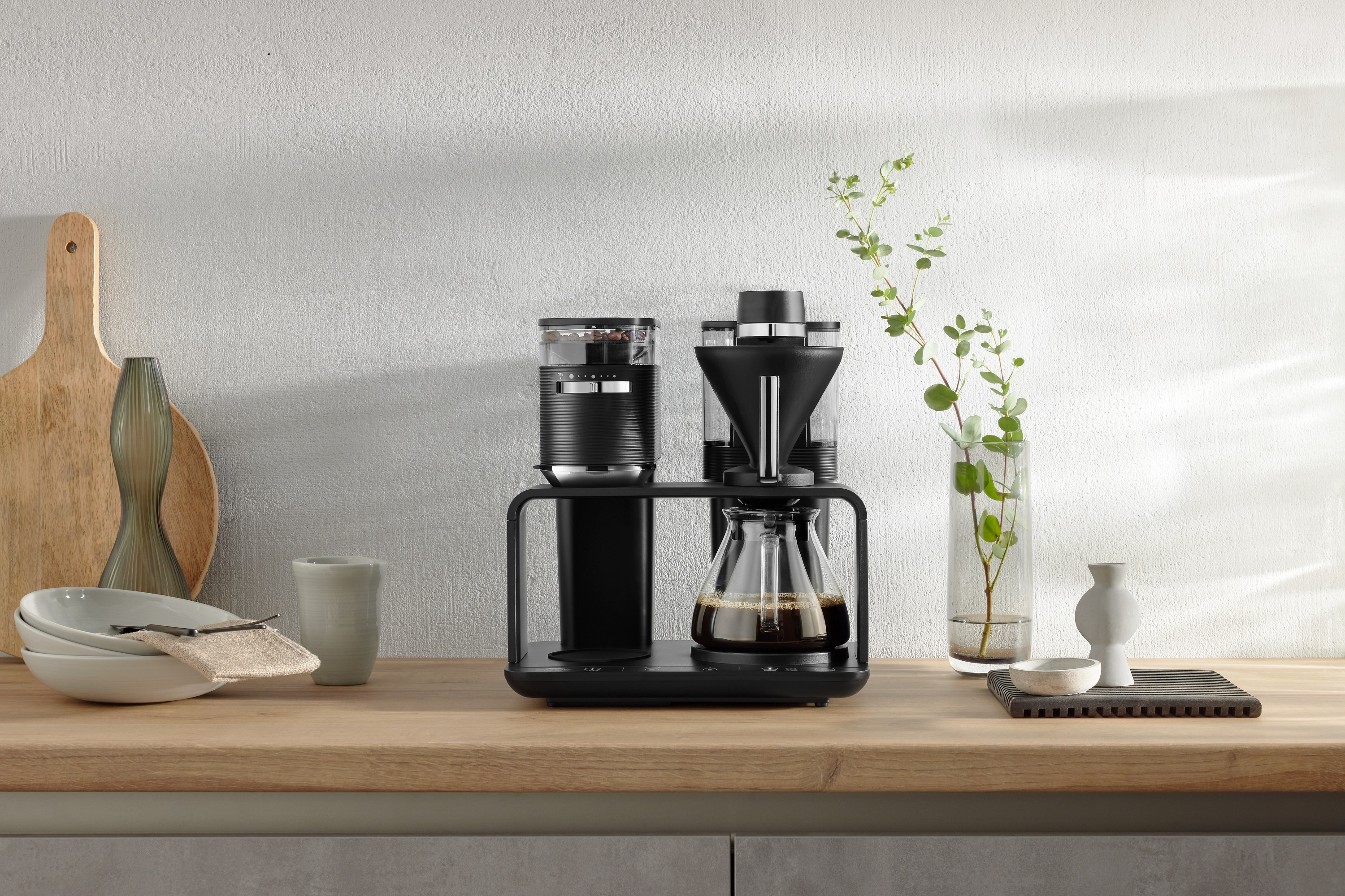 Schwarze Kaffeemaschine mit Mahlwerk und Glaskaraffe.
