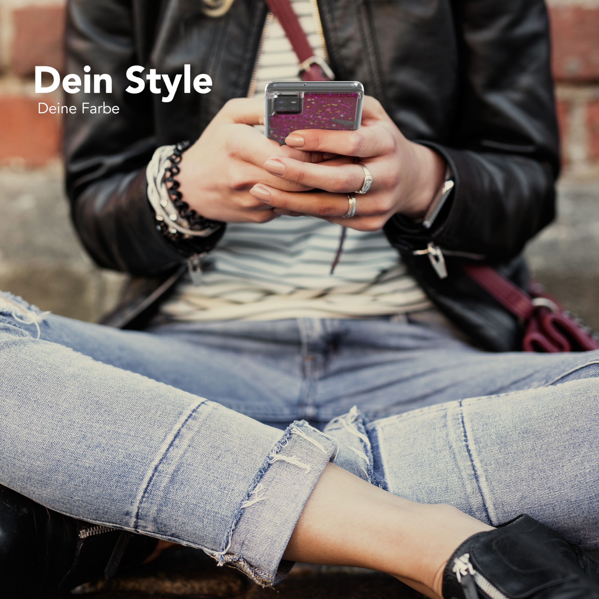 Person hält Handy mit Glitzerhülle, sitzt. Jeans und schwarze Jacke sind sichtbar.