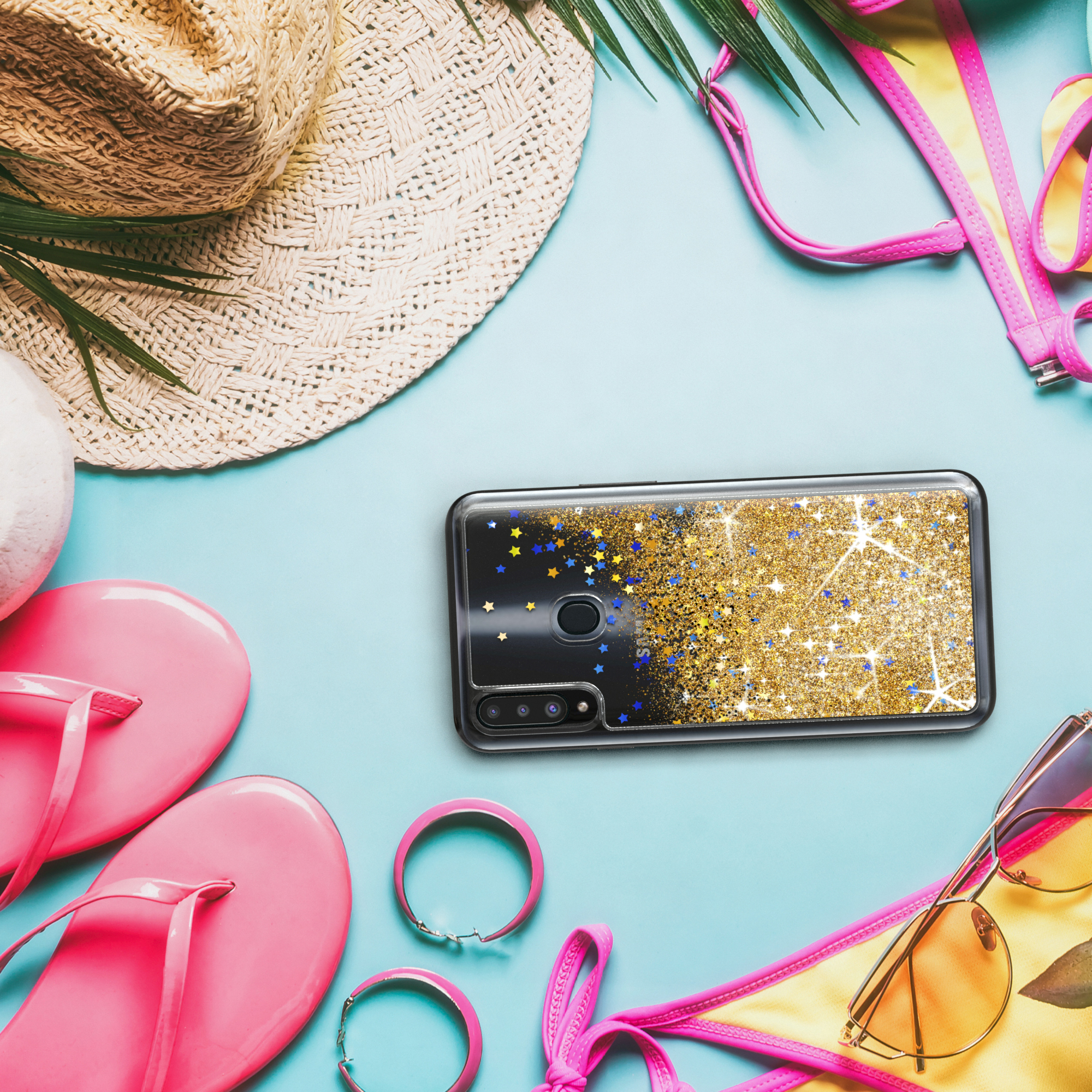 Handyhülle mit goldenem Glitzerdesign, neben Strandaccessoires auf blauem Hintergrund.