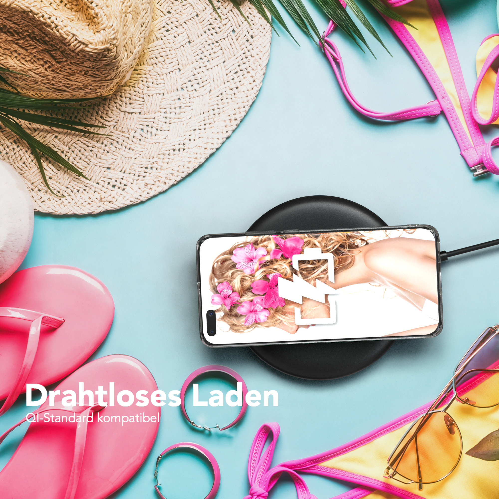 Ein Telefon, das auf einem kabellosen Ladegerät geladen wird, neben Strandaccessoires.