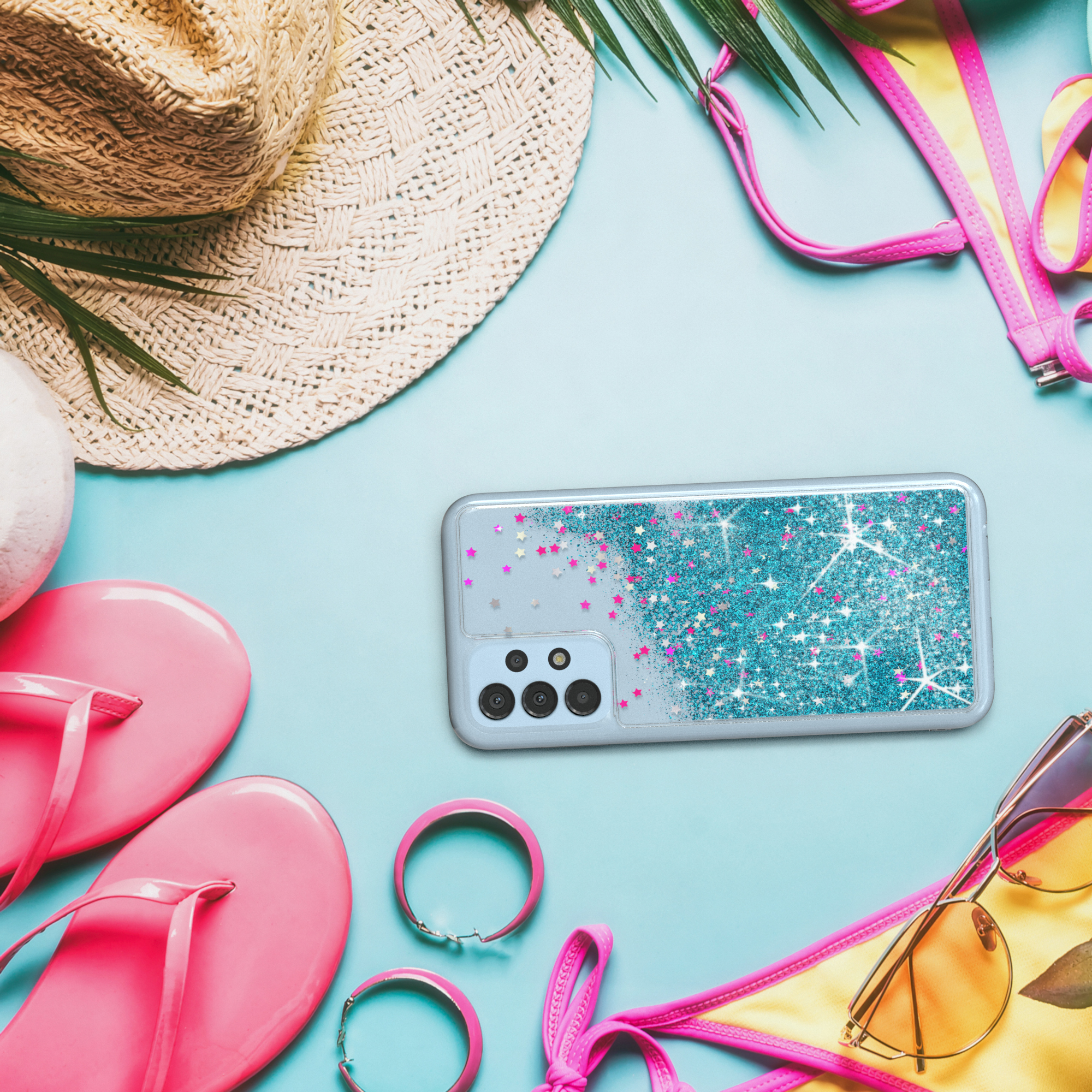 Strandszene mit Telefon in Hülle, umgeben von Accessoires: Hut, Sonnenbrille und Schmuck.