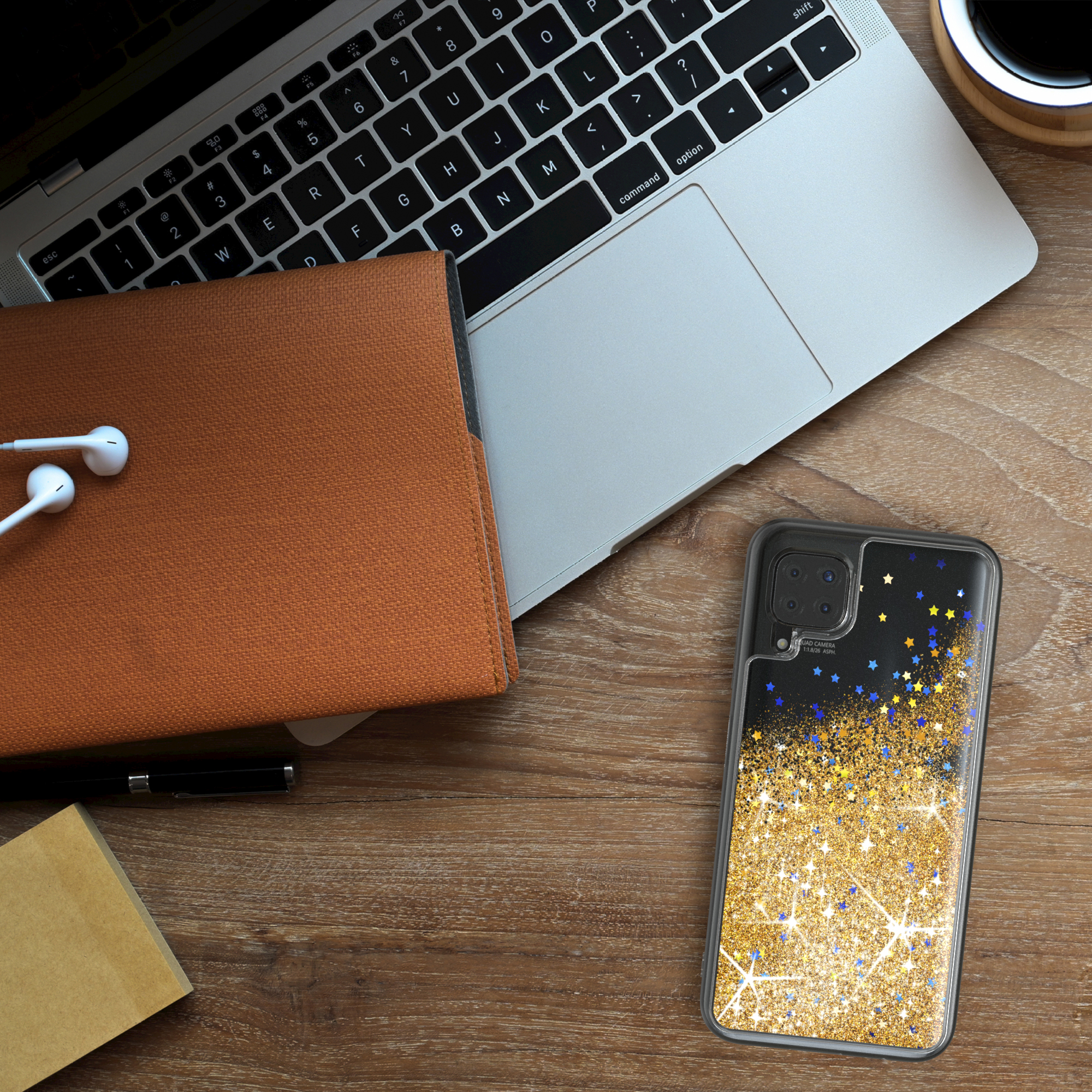 Ein Telefon mit Glitzerhülle auf einem Holzschreibtisch mit Laptop und Kopfhörern.