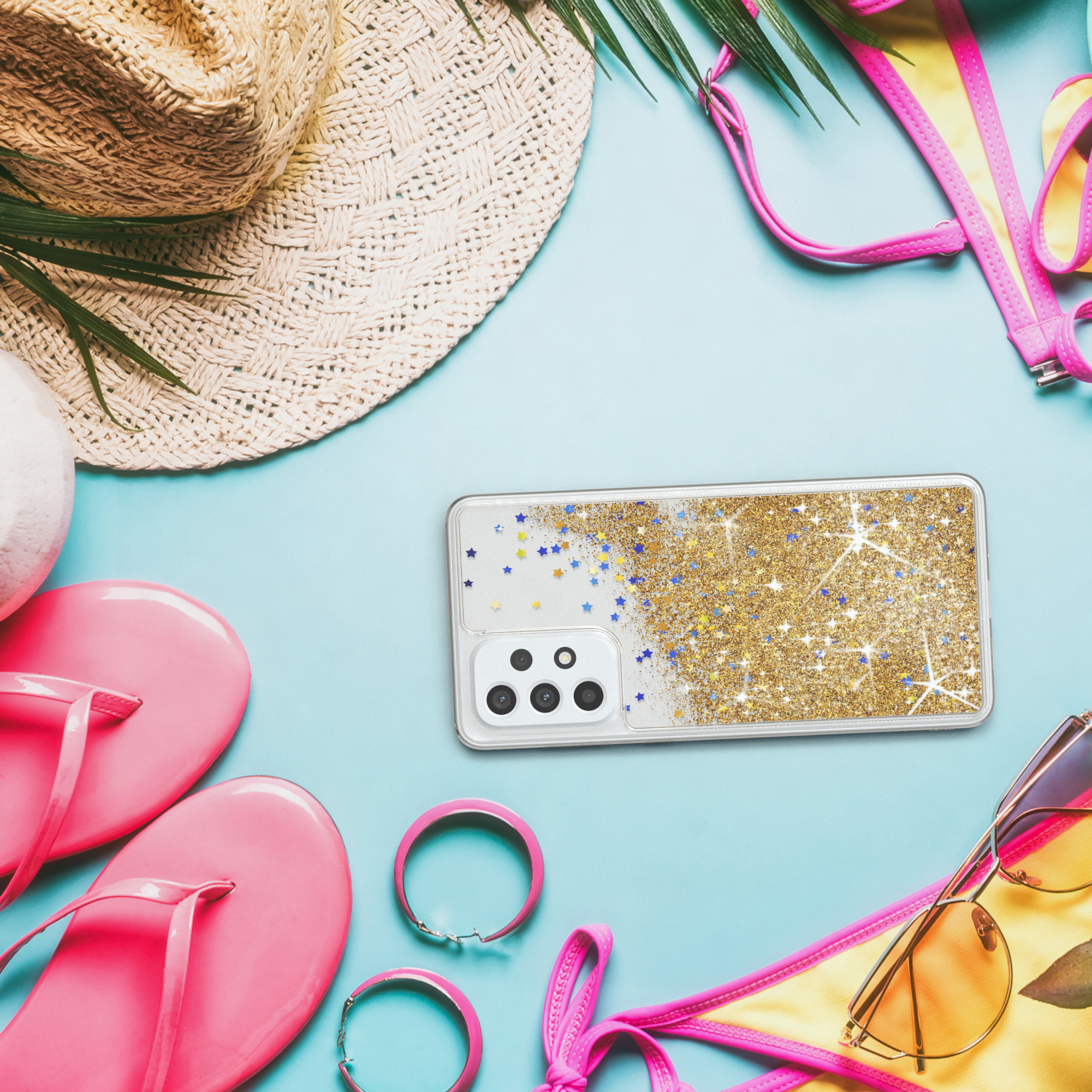 Handyhülle mit goldenem Glitzer. Die Handyhülle befindet sich zwischen Strandutensilien: Hut, Sonnenbrille und Bikini.