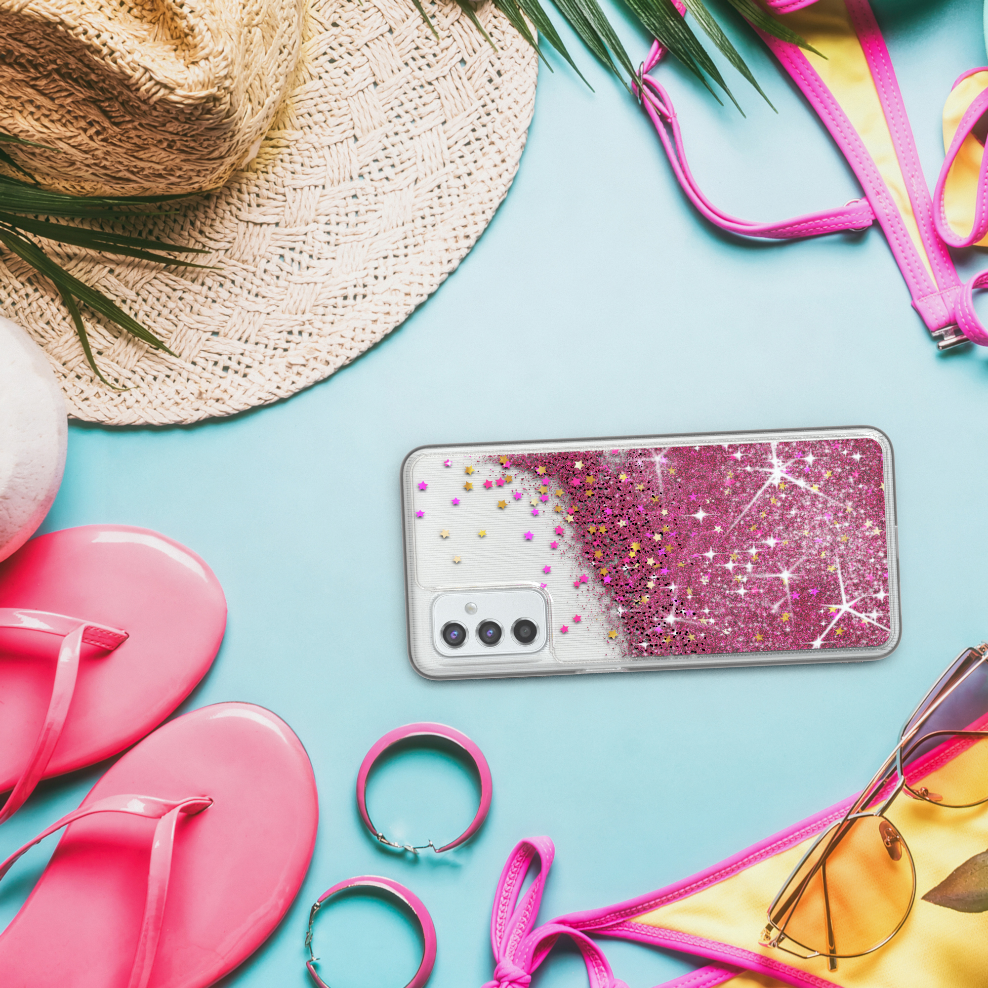 Eine Handyhülle auf blauem Hintergrund mit Strandaccessoires. Rosa Glitzer auf der Hülle.