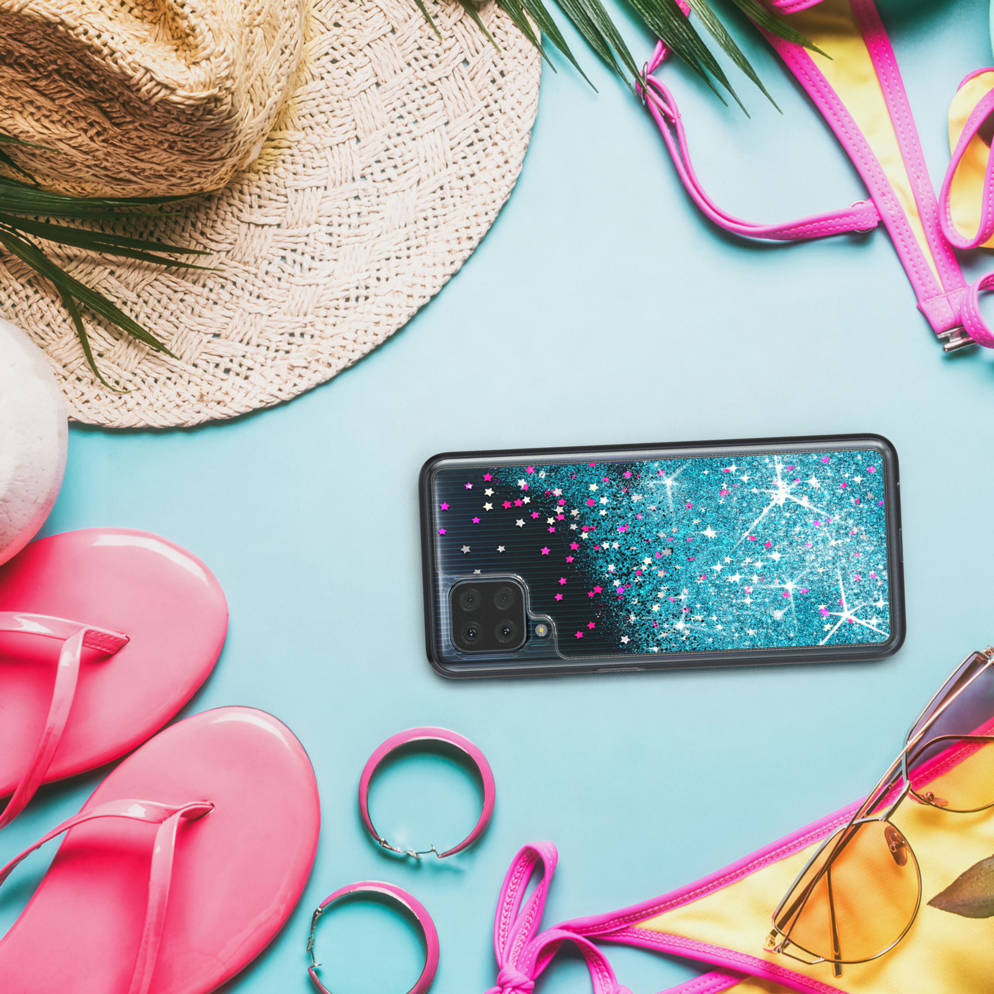 Handyhülle mit rosa Glitzer und Sternen auf einer Strandszene mit Accessoires.