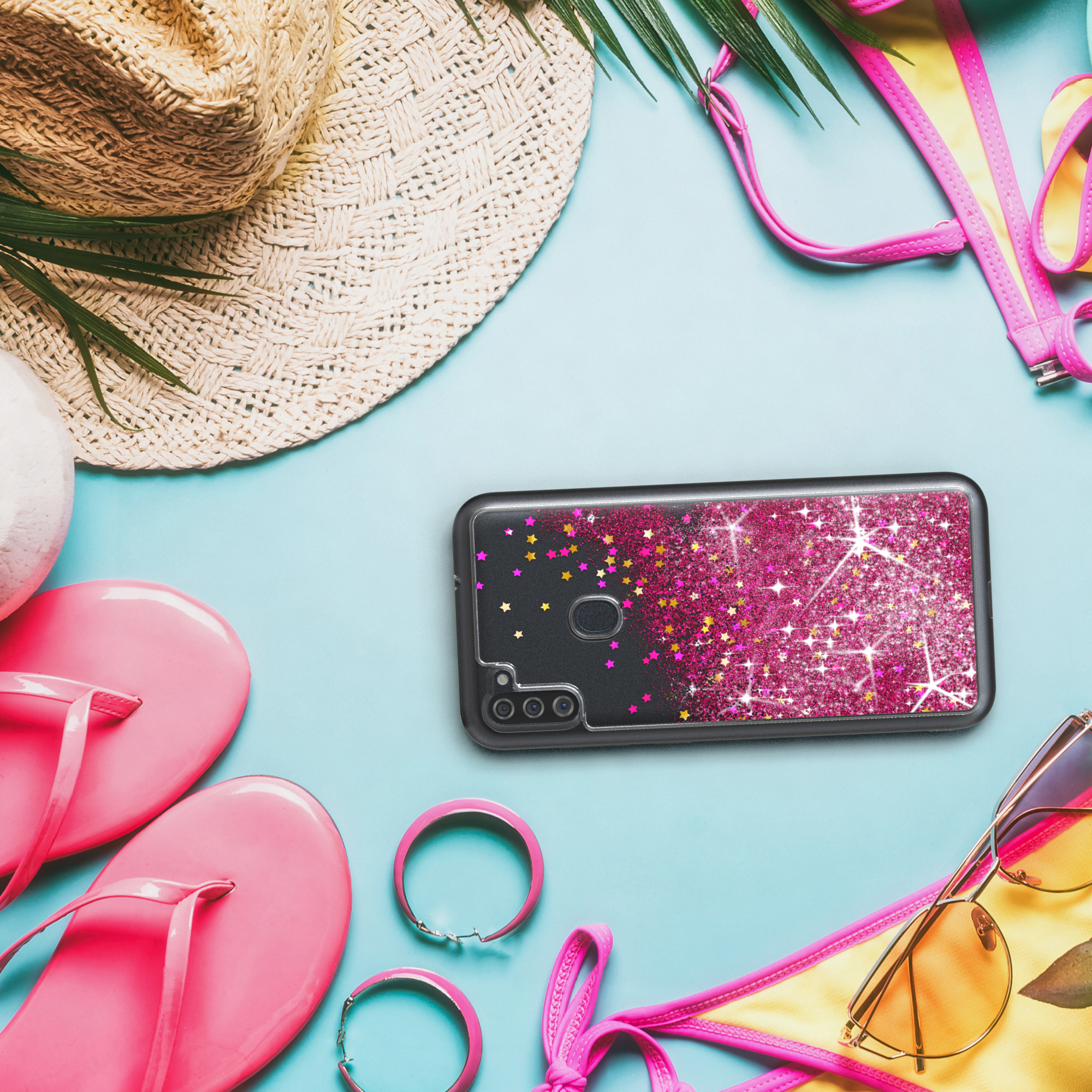 Eine Handyhülle auf blauem Hintergrund mit Strandaccessoires. Rosa Glitzer auf der Hülle.