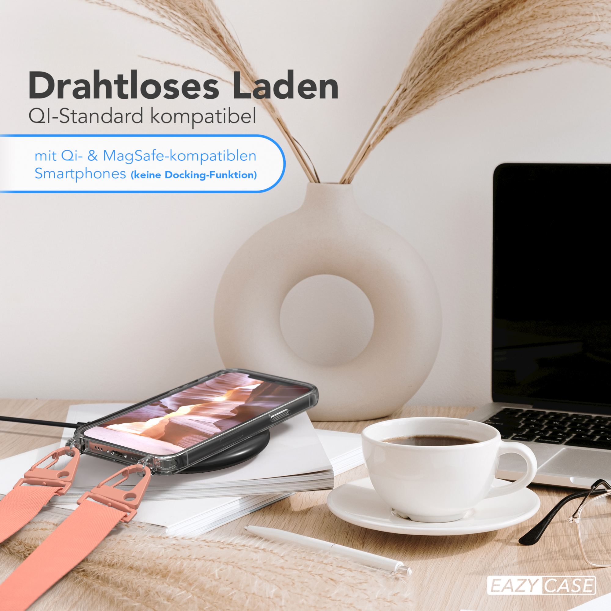 Ein Telefon, ein kabelloses Ladegerät und eine Tasse Kaffee auf einem Schreibtisch. Im Hintergrund ein Laptop.