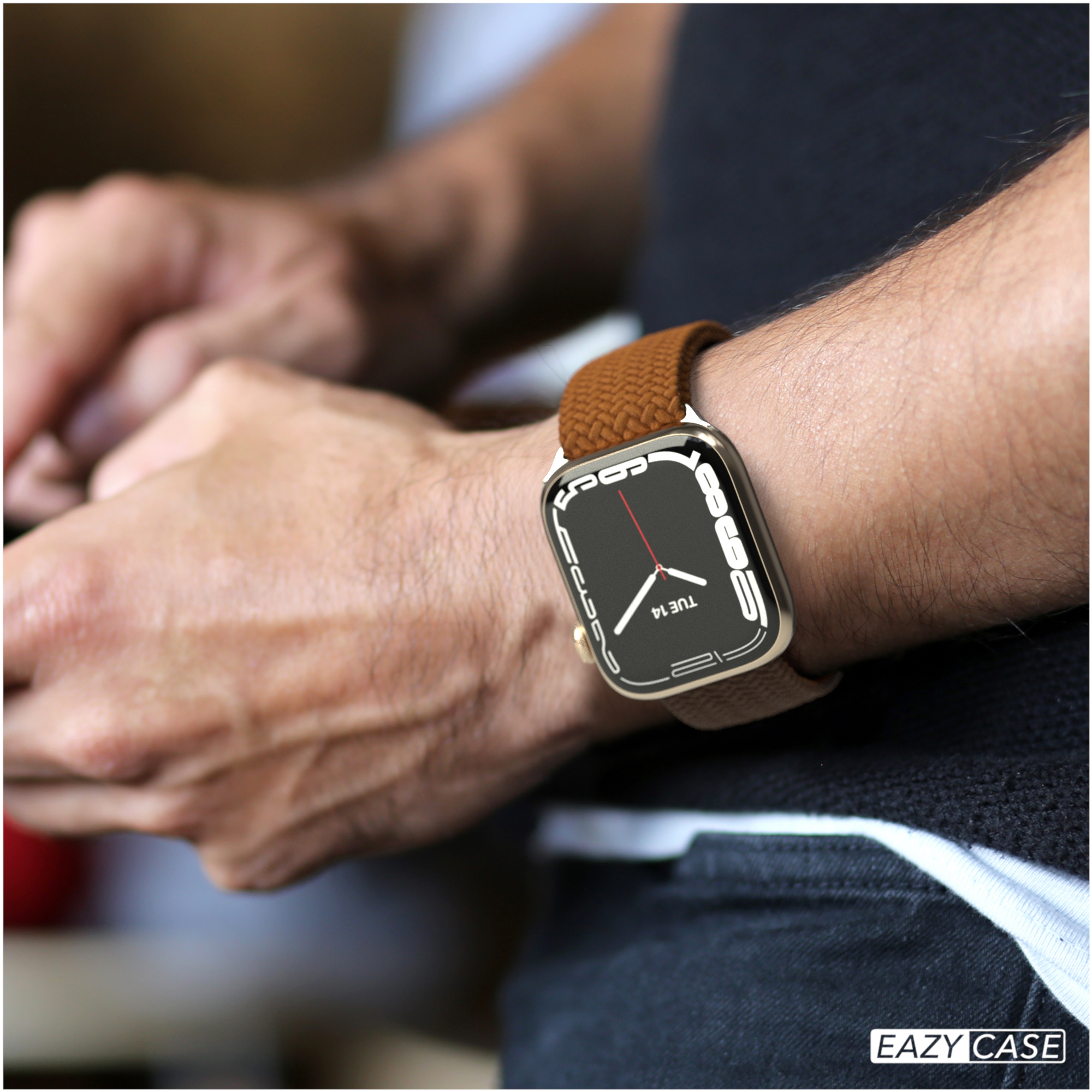 Eine Person, die eine goldene Uhr mit braunem Armband trägt.