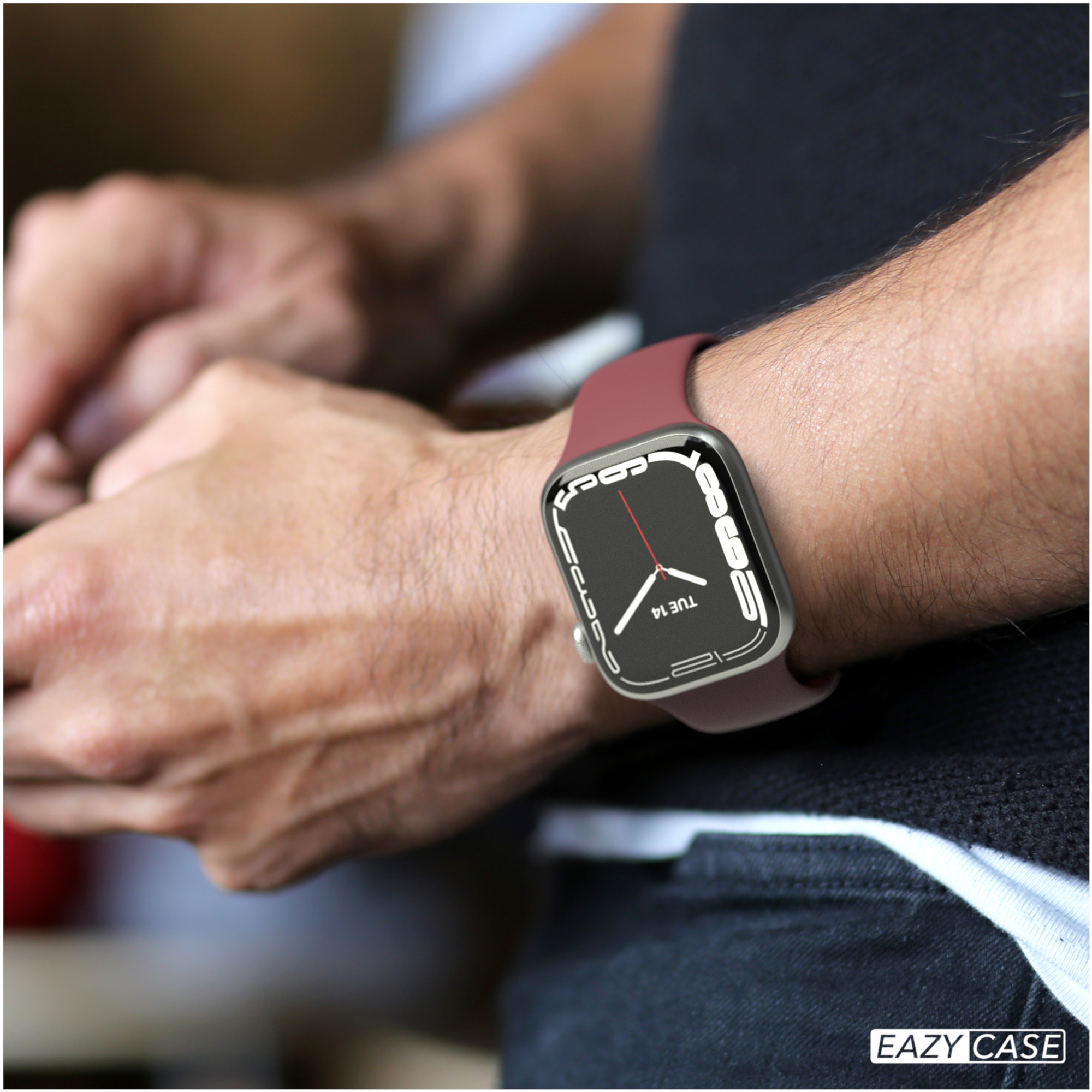 Ein Arm mit einer Uhr, die die Zeit anzeigt, mit einem bordeauxroten Armband.