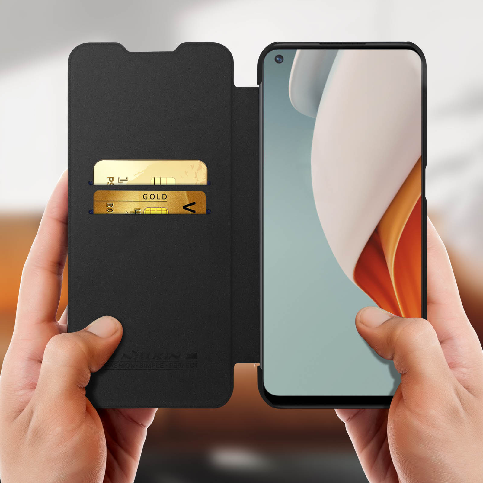 Schwarze Handyhülle mit zwei goldenen Karten sichtbar. Telefonbildschirm rechts.