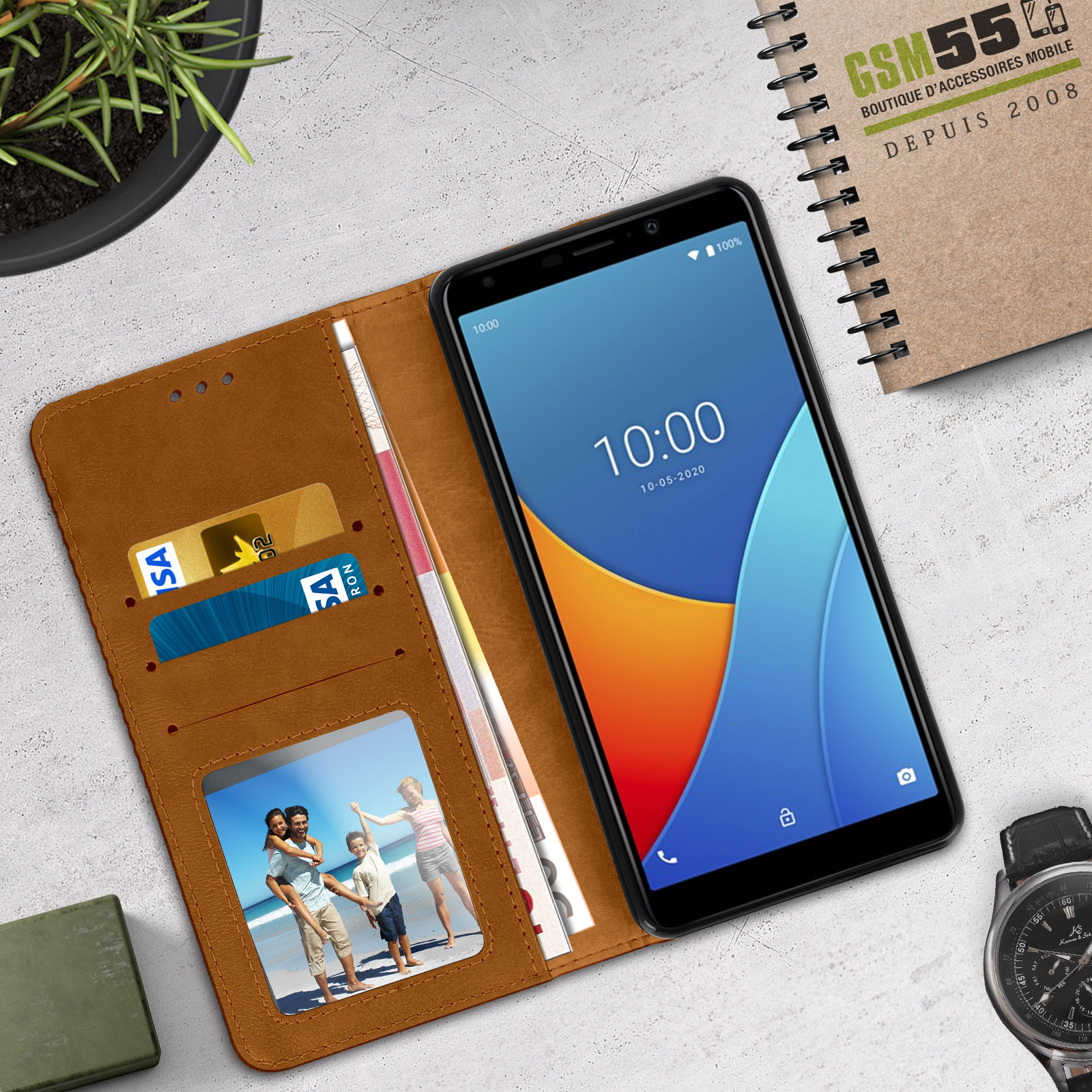 Funda de teléfono marrón abierta con un teléfono dentro. El teléfono muestra una interfaz.