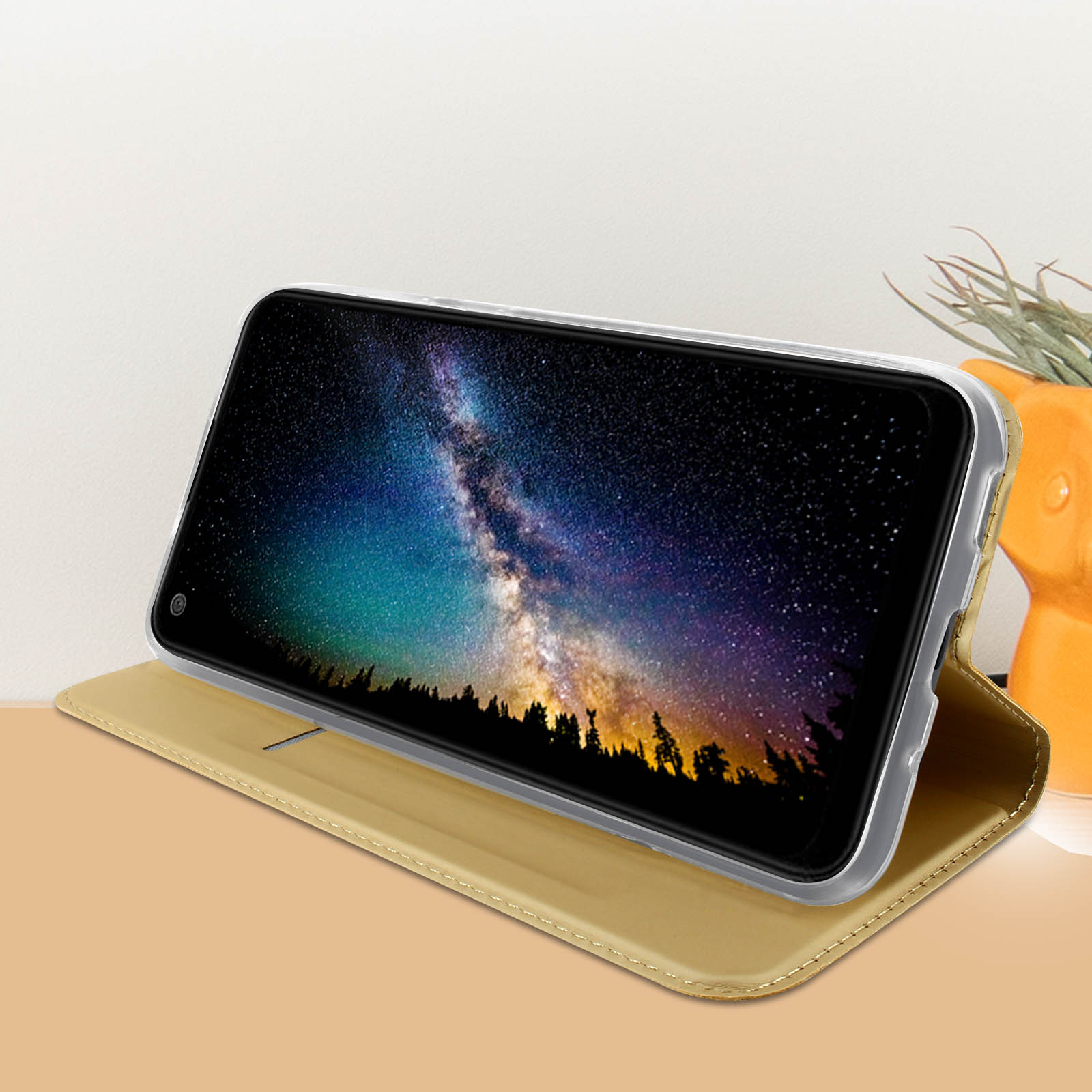 Un tablet nero in una custodia dorata che mostra un cielo notturno con una galassia.