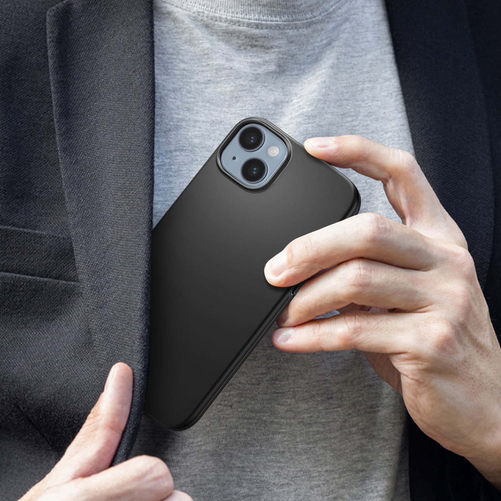 Osoba trzymająca czarny telefon w czarnym etui, w kieszeni. Szara koszula i czarna kurtka mężczyzny.