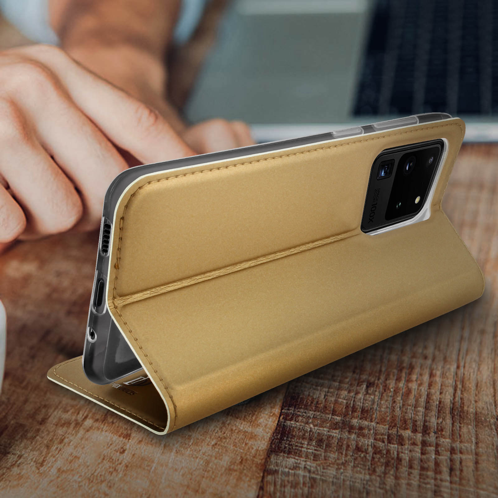 Eine Hand, die eine goldene Handyhülle hält. Das Telefon ist goldfarben.