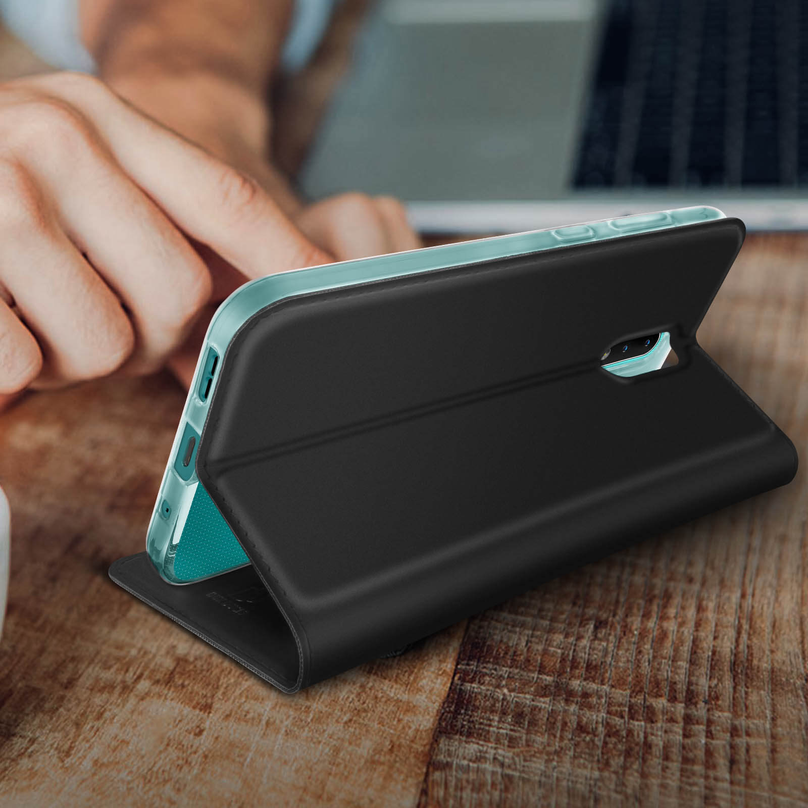 Una custodia per telefono nera aperta, su un tavolo di legno. Il telefono è nella custodia. Lo sfondo è sfocato.