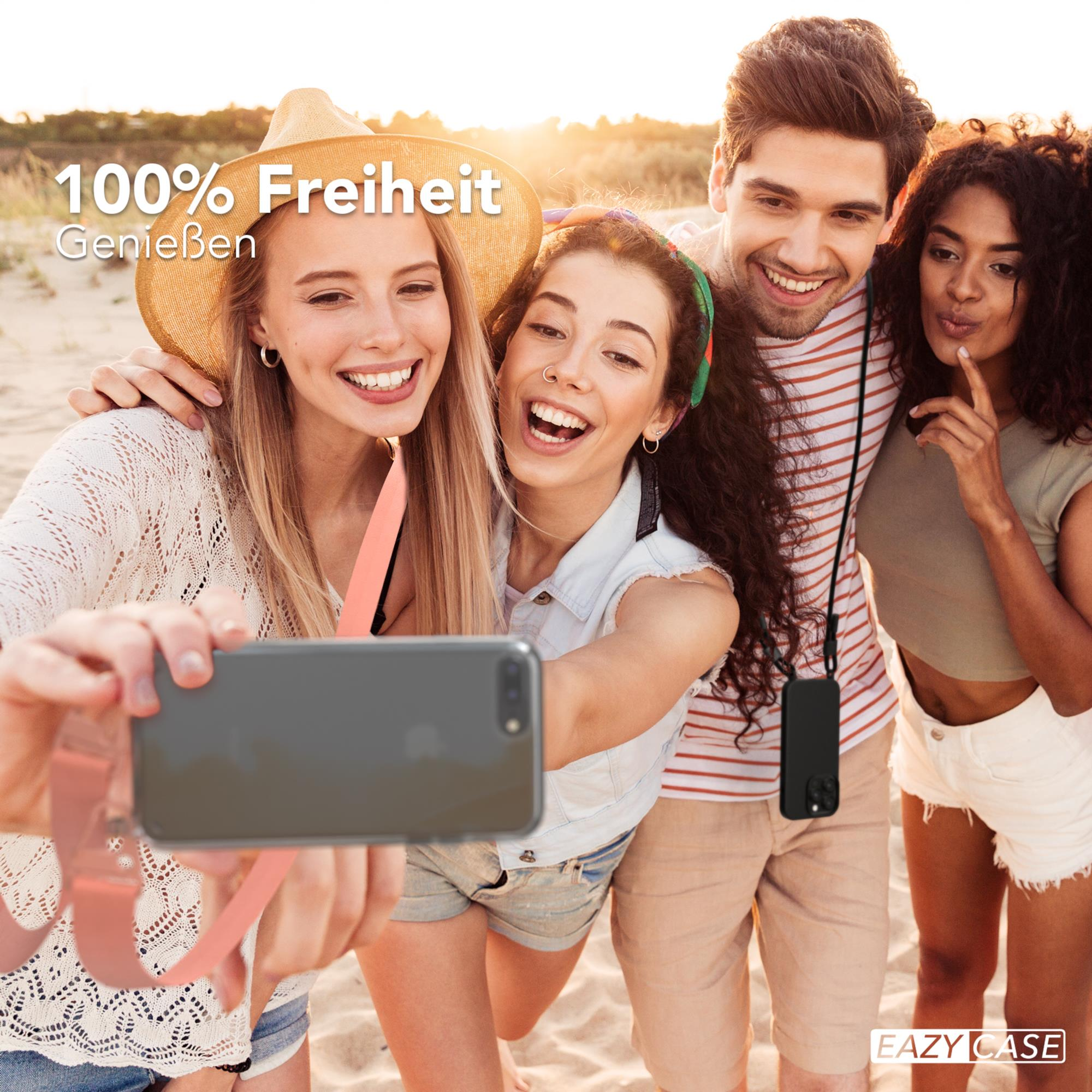 Vier lächelnde Personen machen ein Selfie mit einem Telefon am Strand, tragen ein Lanyard.