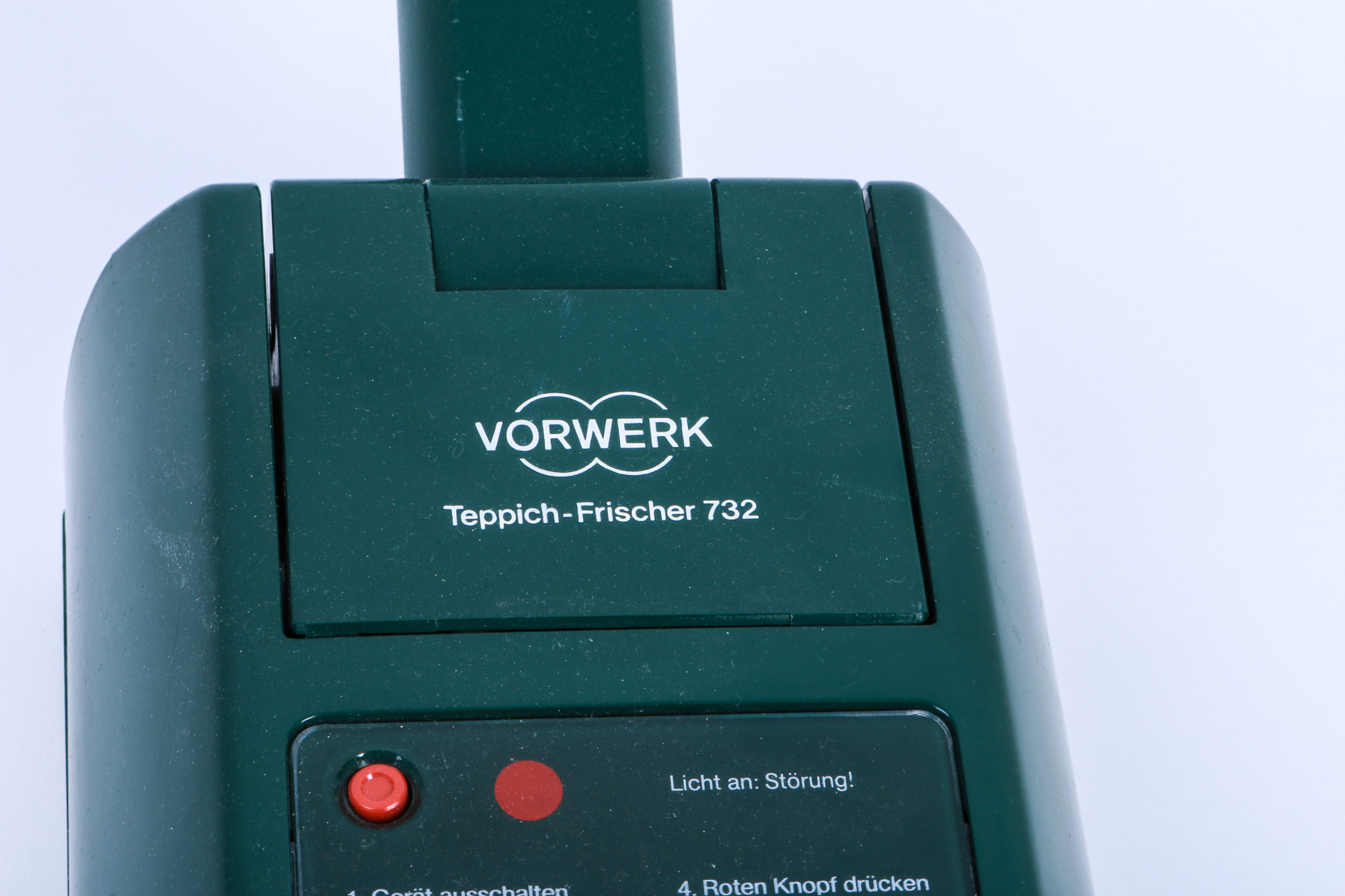 Nahaufnahme eines grünen Vorwerk Teppichreinigers mit Vorwerk Logo und rotem Licht.