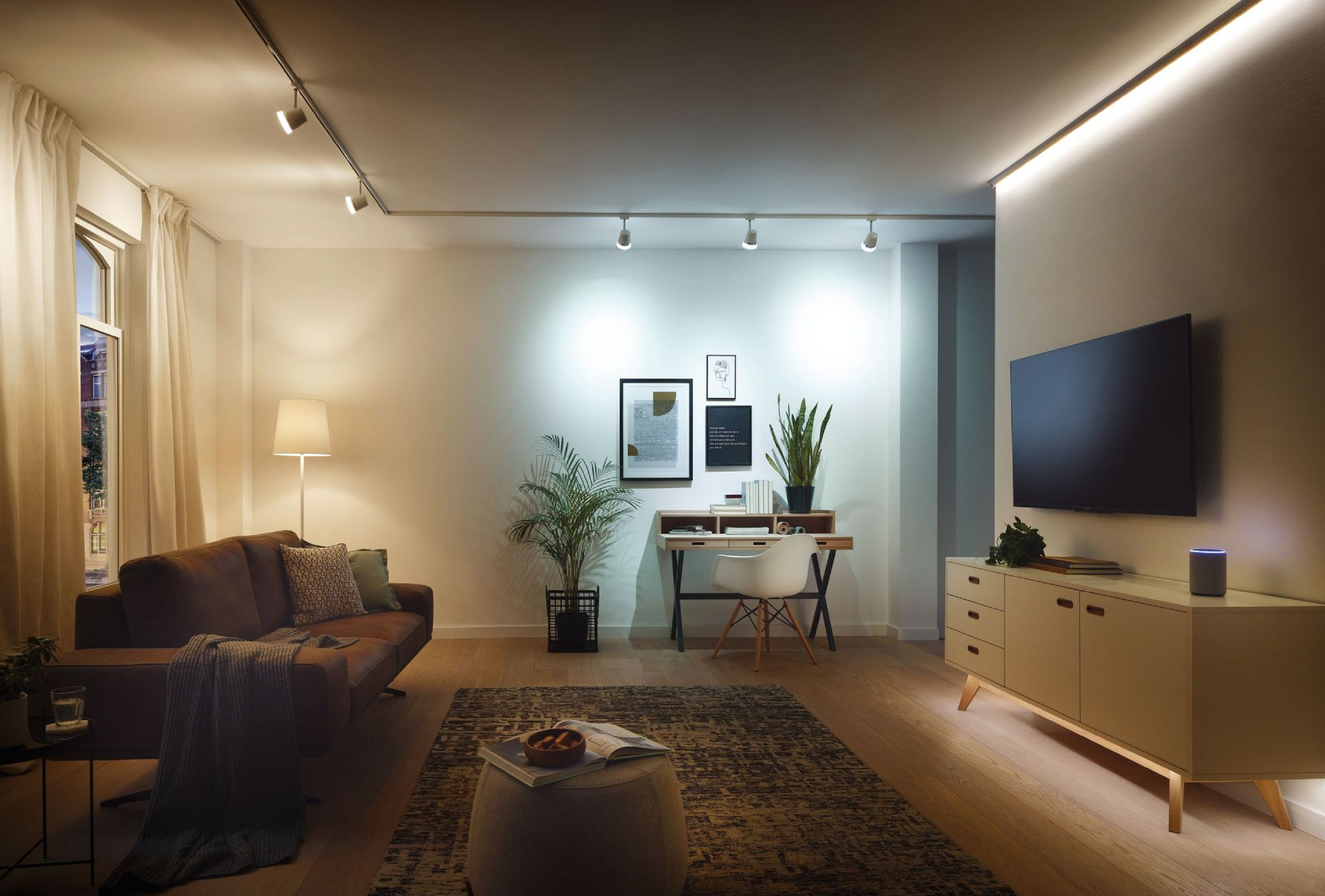 Nowoczesny salon z oświetleniem, sofą, roślinami i telewizorem.