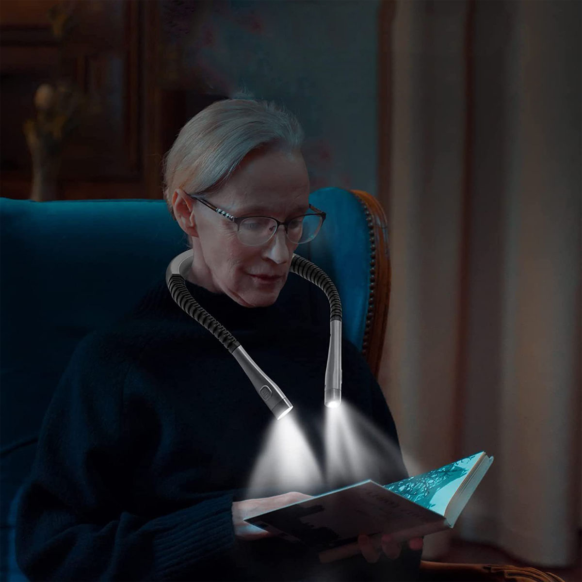 Eine ältere Frau, die ein Nackenlicht trägt und ein Buch liest. Das Licht beleuchtet die Seiten des Buches.