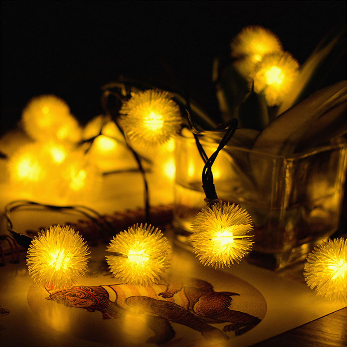Lichterketten mit gelb leuchtenden Glühbirnen. Einige sind scharf gestellt. Dunkler Hintergrund. Eine Glasvase ist sichtbar.