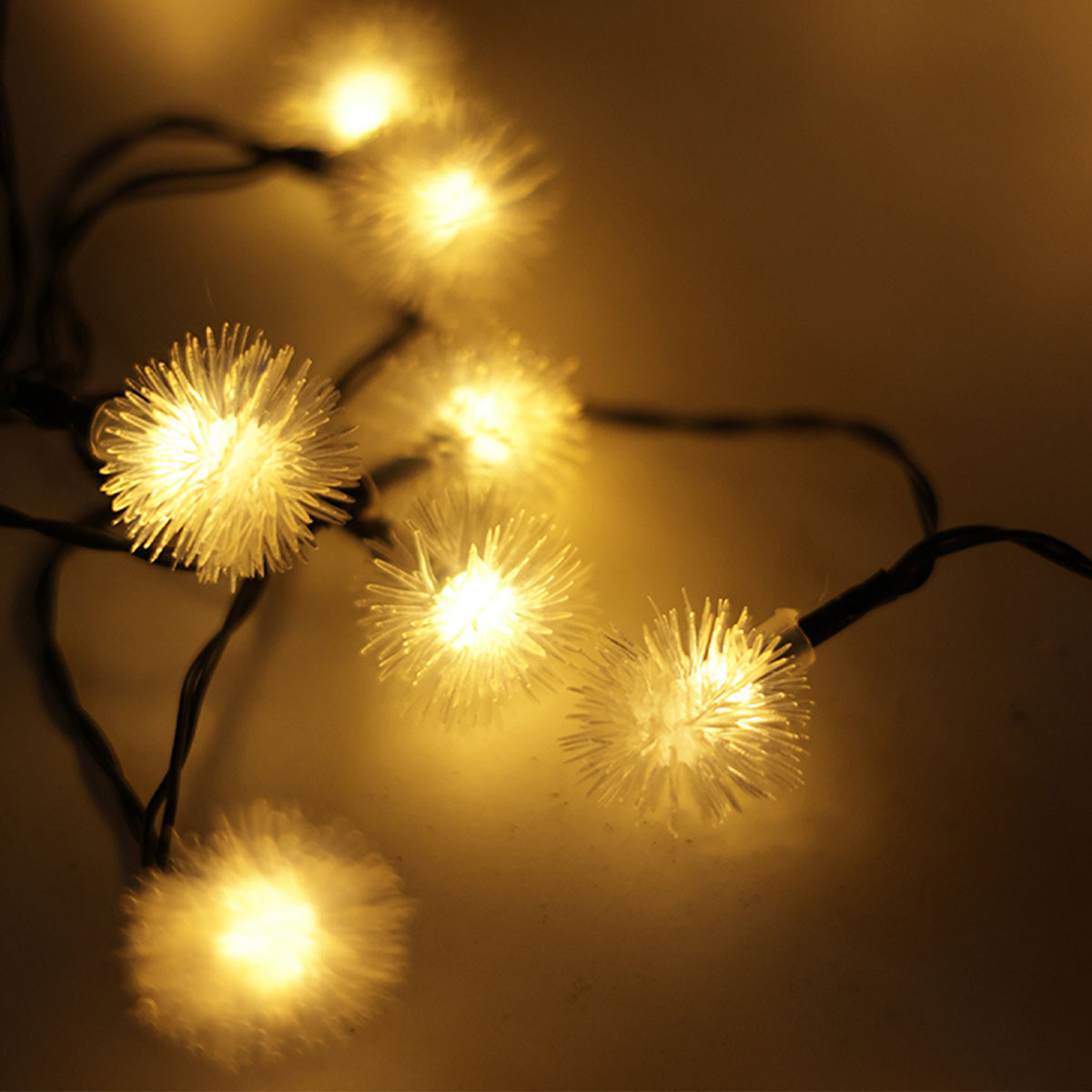 Nahaufnahme von Lichterketten. Kleine, weiße, sternförmige Lichter leuchten auf dunklem Hintergrund.