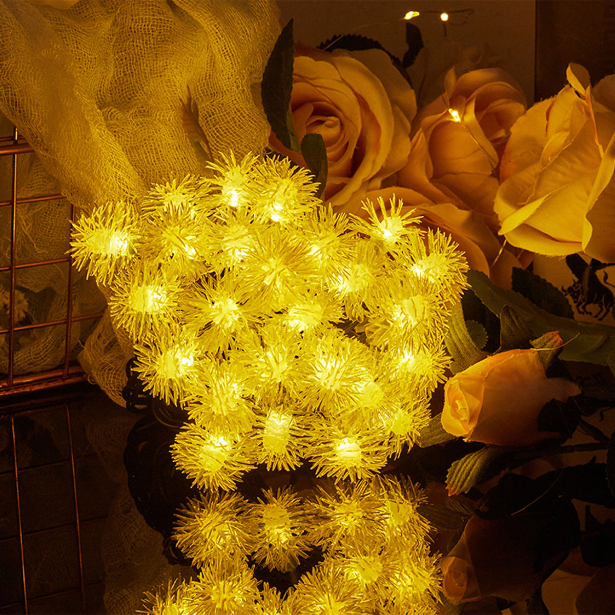 Gelbe Lichterkette in einem Blumenarrangement.