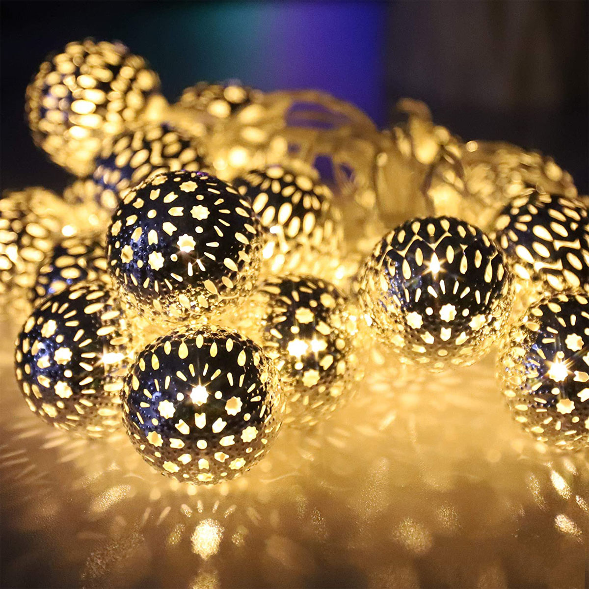 Nahaufnahme von dekorativen Lichtern. Die Lichter sind kugelförmig mit gemusterten Aussparungen und leuchten warm.