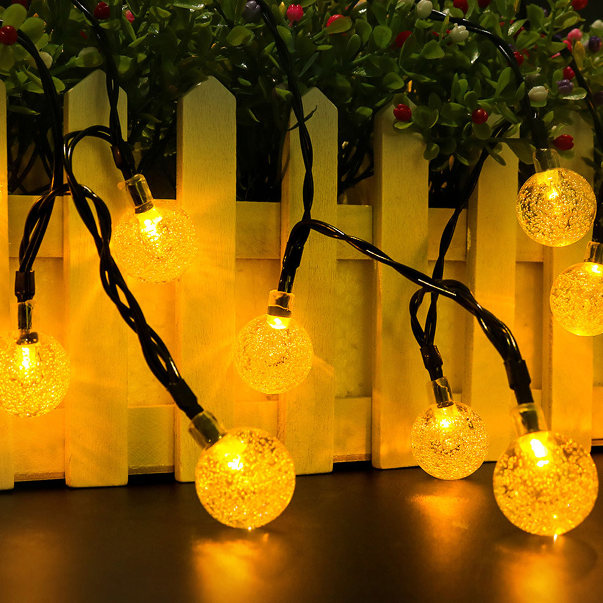 Lichterkette mit gelben, kugelförmigen Lichtern. Die Lichter sind an einem schwarzen Draht.