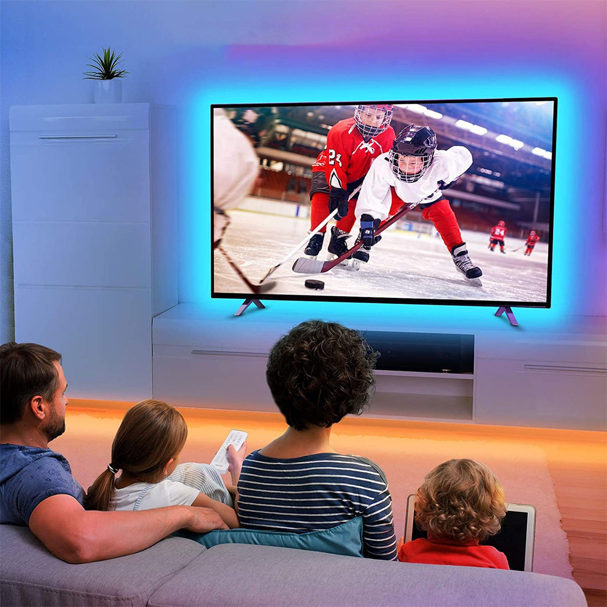Una familia ve hockey en la televisión. El televisor tiene una luz azul a su alrededor.
