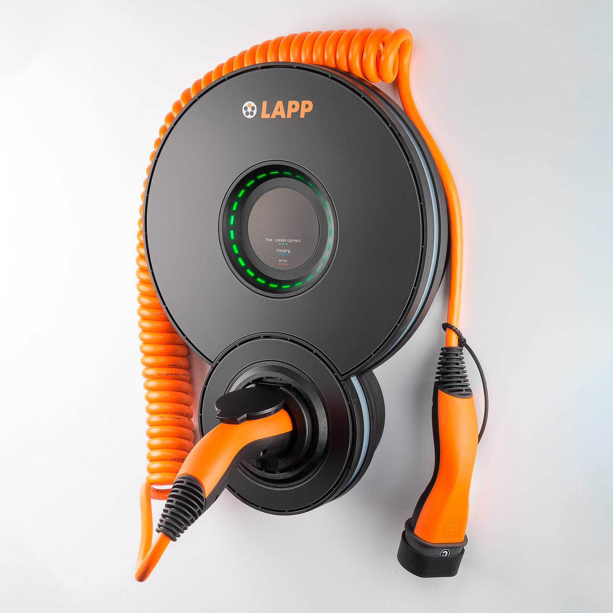 Schwarze und orangefarbene EV-Ladestation an einer weißen Wand. Das Kabel ist aufgerollt.