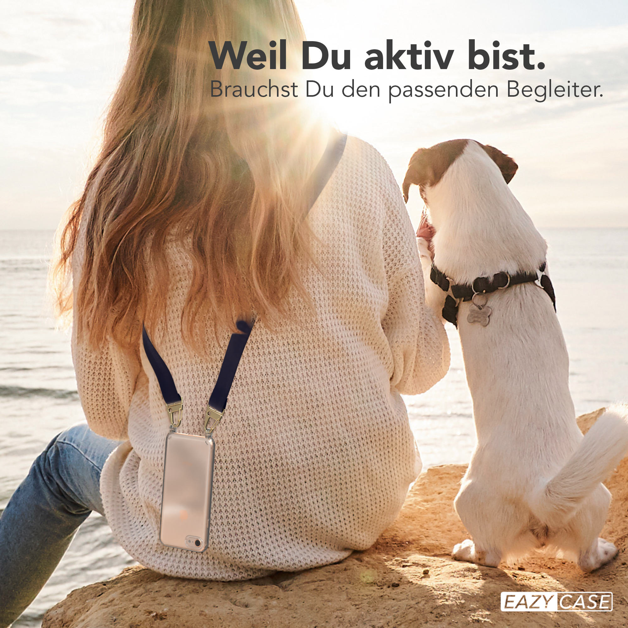 Frau mit Handy an der Leine sitzt mit Hund. Sonnige Szene.
